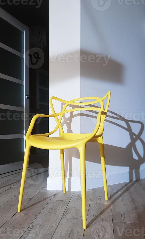 Yellow plastic chair near the wall with a shadow in the interior of the house. photo