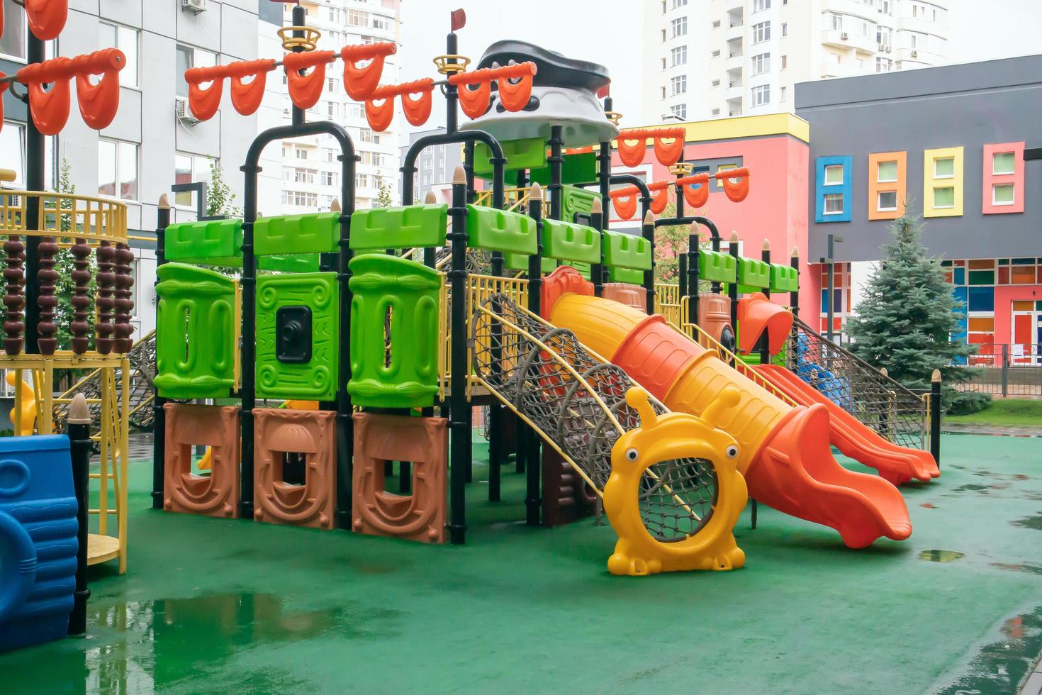 The courtyard of a high-rise building with a modern large playground made of wood and plastic on a rainy summer day without people. Ukraine, Kiev - August 19, 2021. photo
