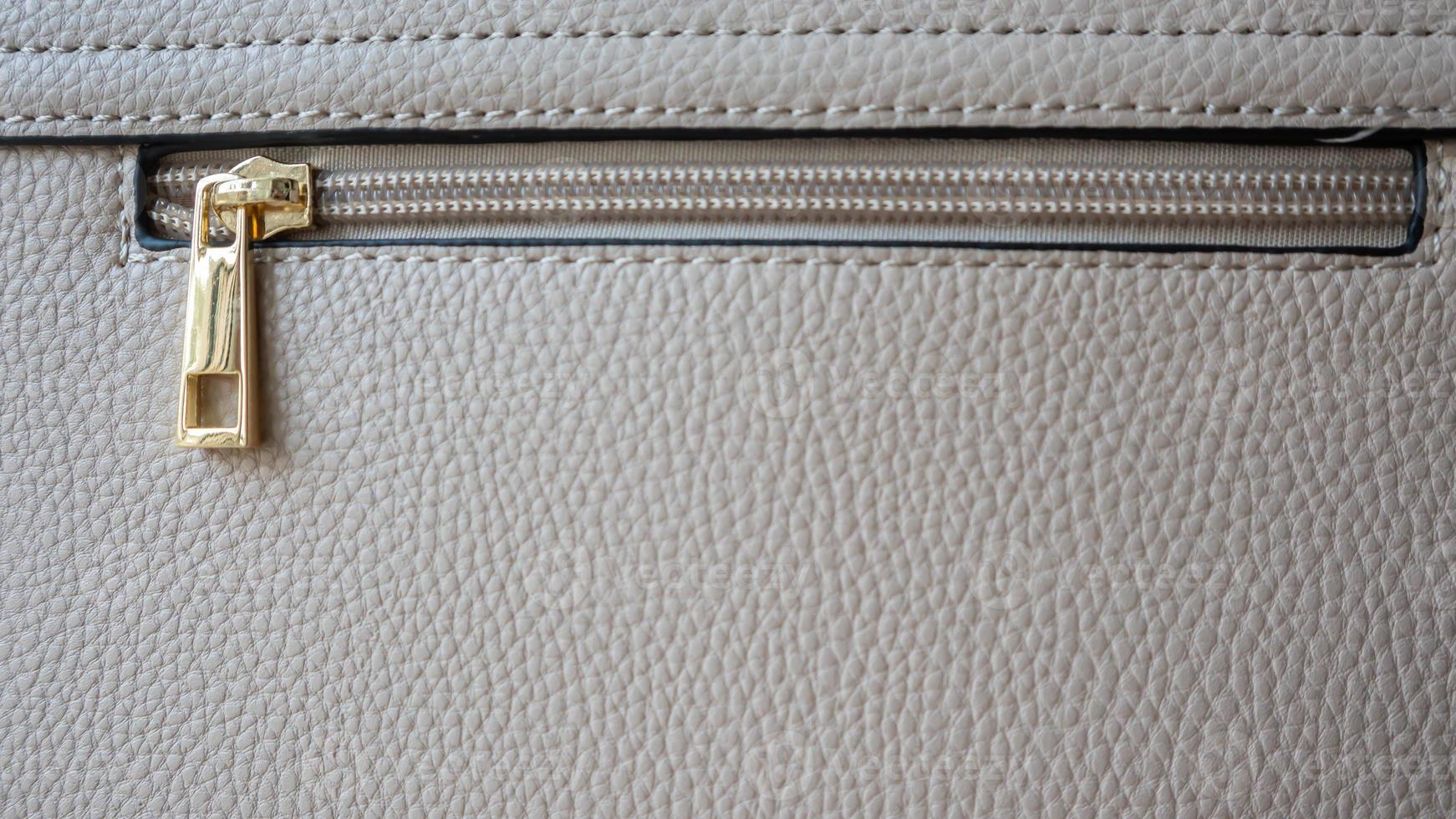 textura de cuero natural o artificial. fragmento de una bolsa beige o empolvada con cremallera y costuras. elemento de diseño de bolsa con cremallera o cierre. textura de piel bovina con serpiente. fotografía macro, enfoque selectivo. foto