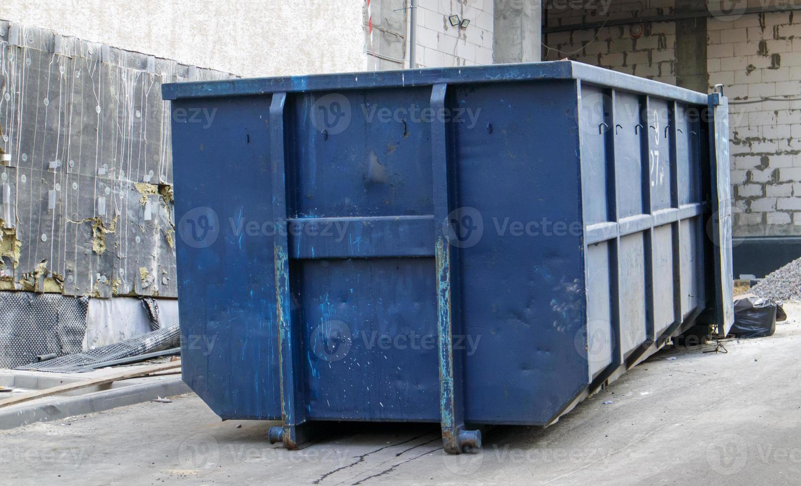 Metal durable blue industrial trash bin for outdoor trash at construction site. Large waste basket for household or industrial waste. A pile of waste. photo