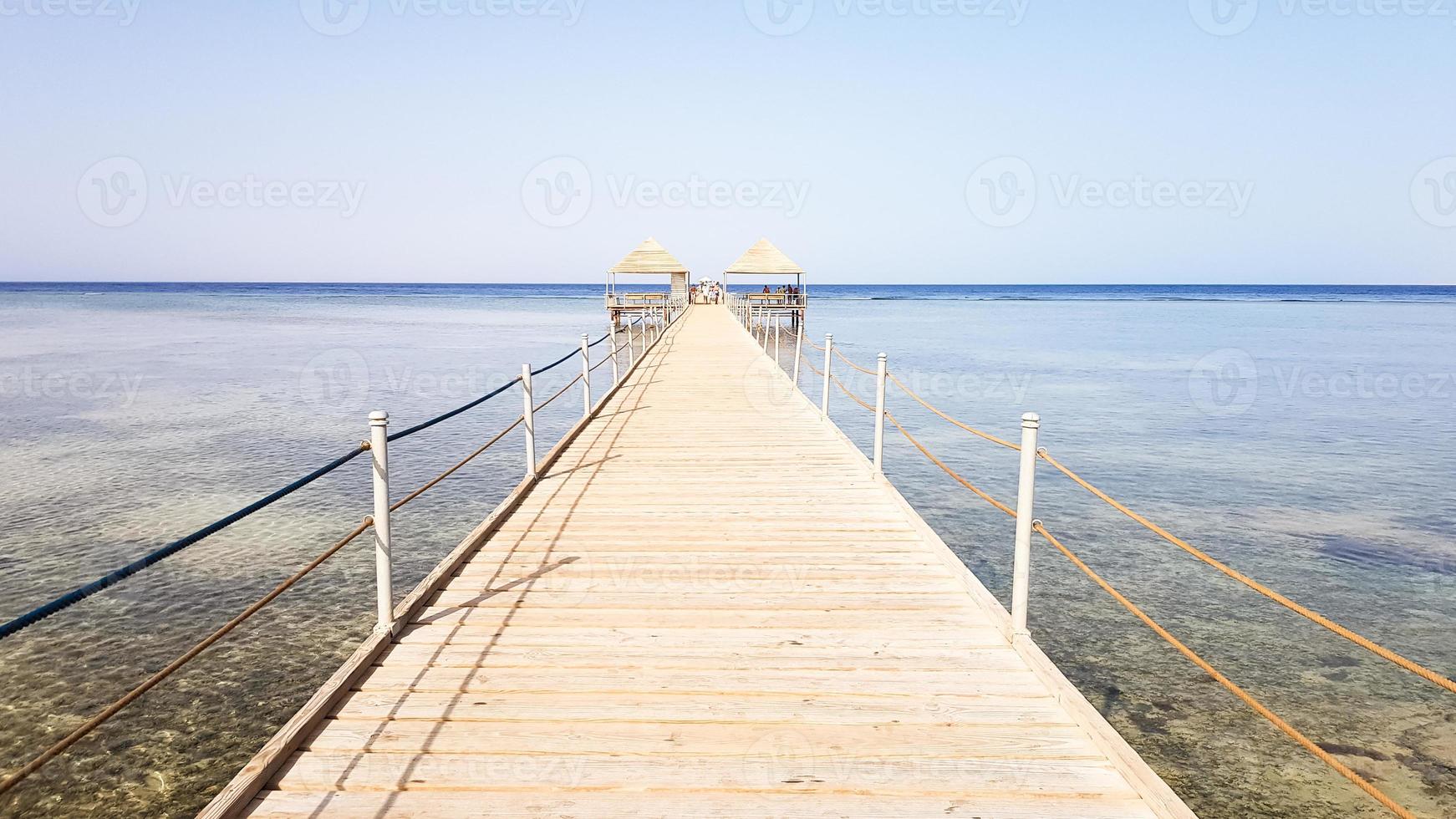 pontón largo en el mar rojo en egipto. pontón para descenso al agua. Puente de madera en el territorio del hotel amway en Sharm el Sheikh con vallas metálicas y una cuerda sobre el mar con olas foto