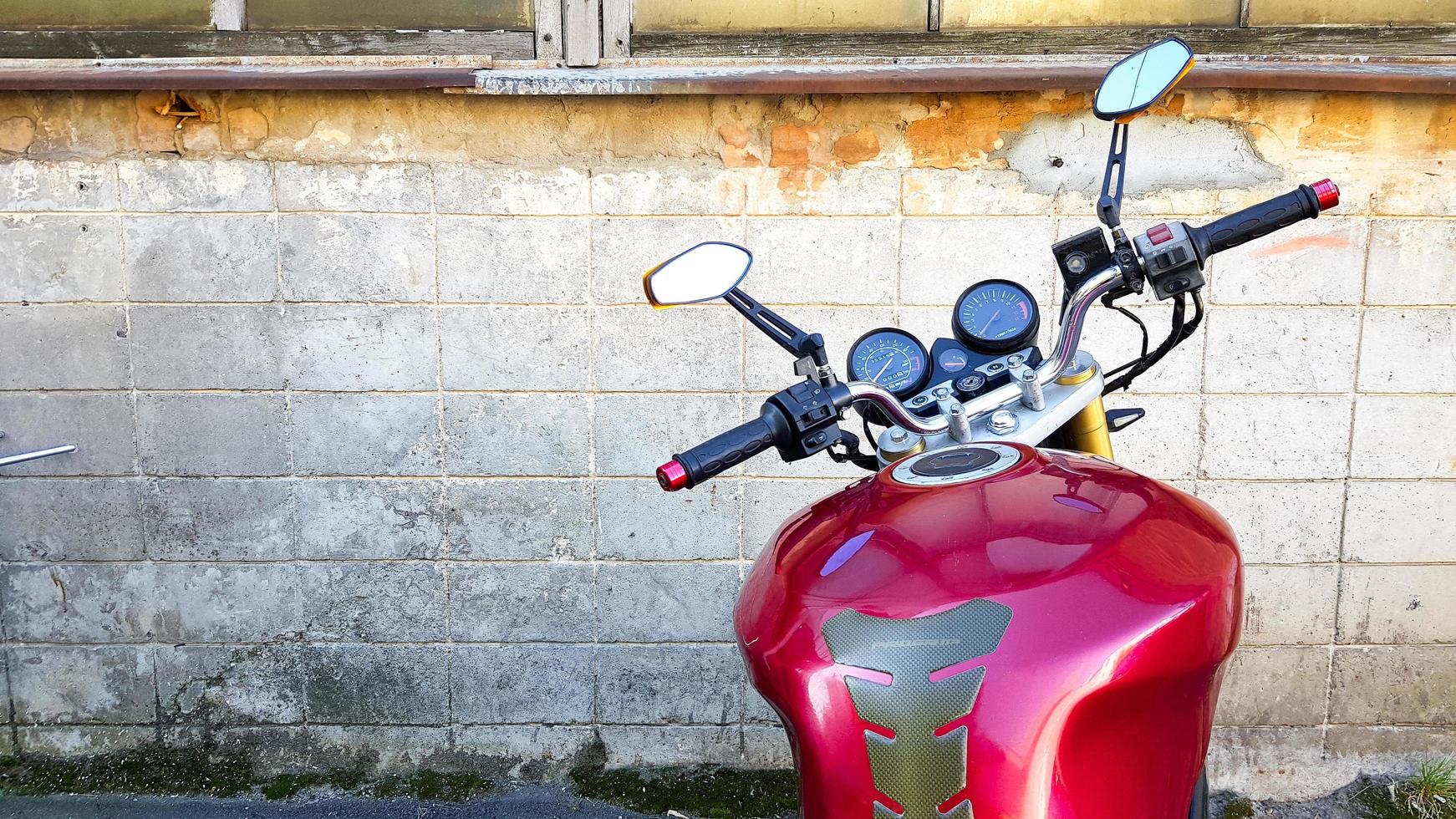 Ukraine, Kiev - September 8, 2019. Red motorcycle parked in a gray brick wall. First-person view, dashboard and steering wheel photo