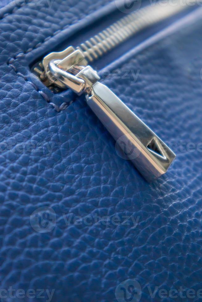 Natural or artificial leather texture. Fragment of a blue bag with a zipper and stitching. Zipper or clasp bag design element. Bovine skin texture with snake. Macro photo, selective focus. photo