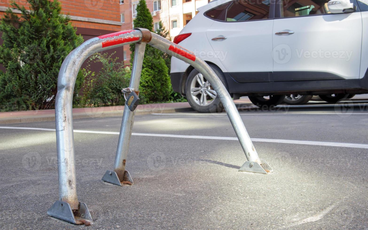 Manual gray galvanized metal parking barrier with lock. Parking lock device. Parking barrier installed. A foldable barrier prevents the vehicle from stopping at this point. Reserved seat. photo