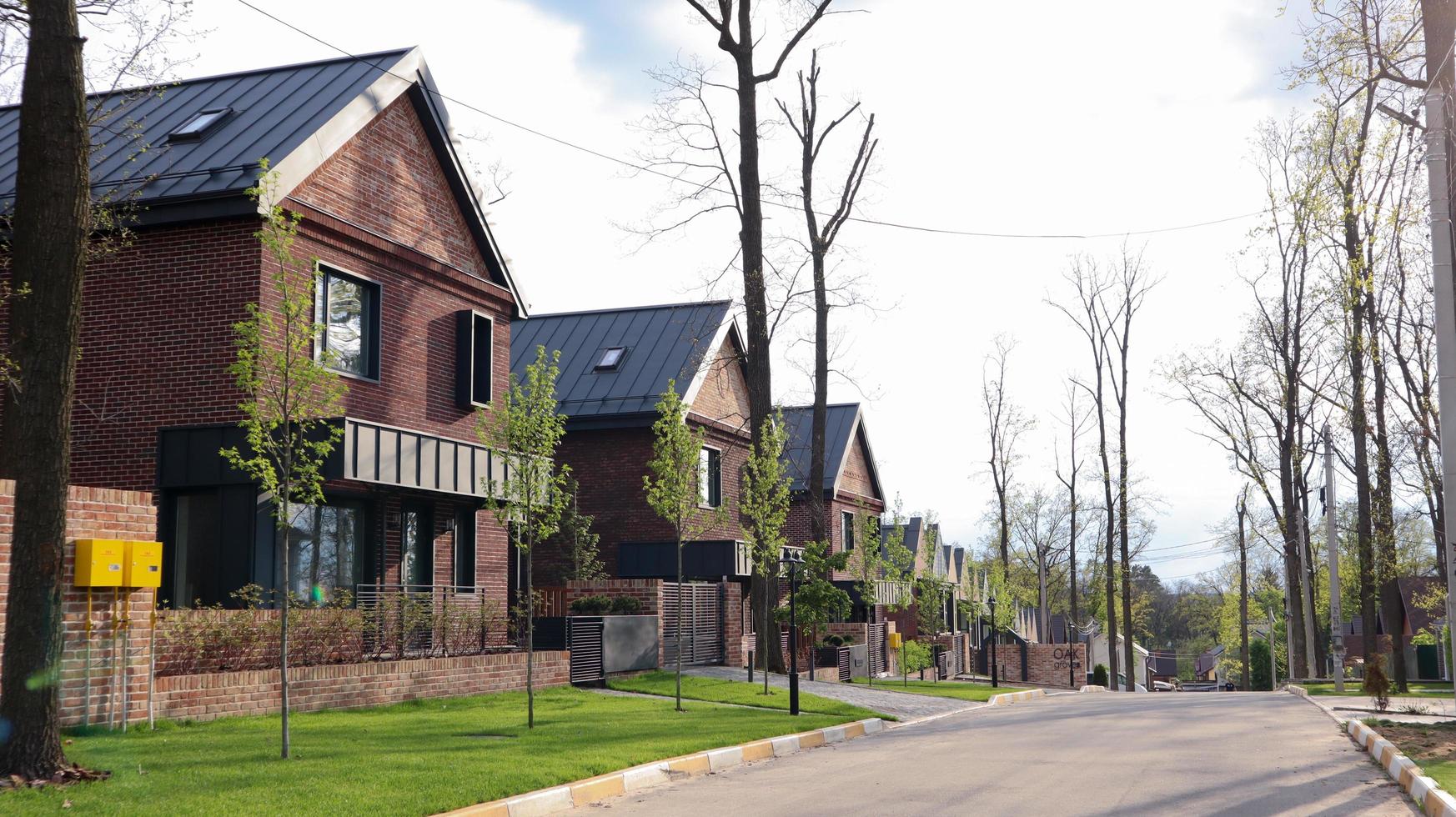 una calle con casas y césped bien cuidado en un barrio típico. marco hecho de pequeñas casas de campo americanas de ladrillo marrón. ucrania, irpin - 07 de junio de 2021. foto