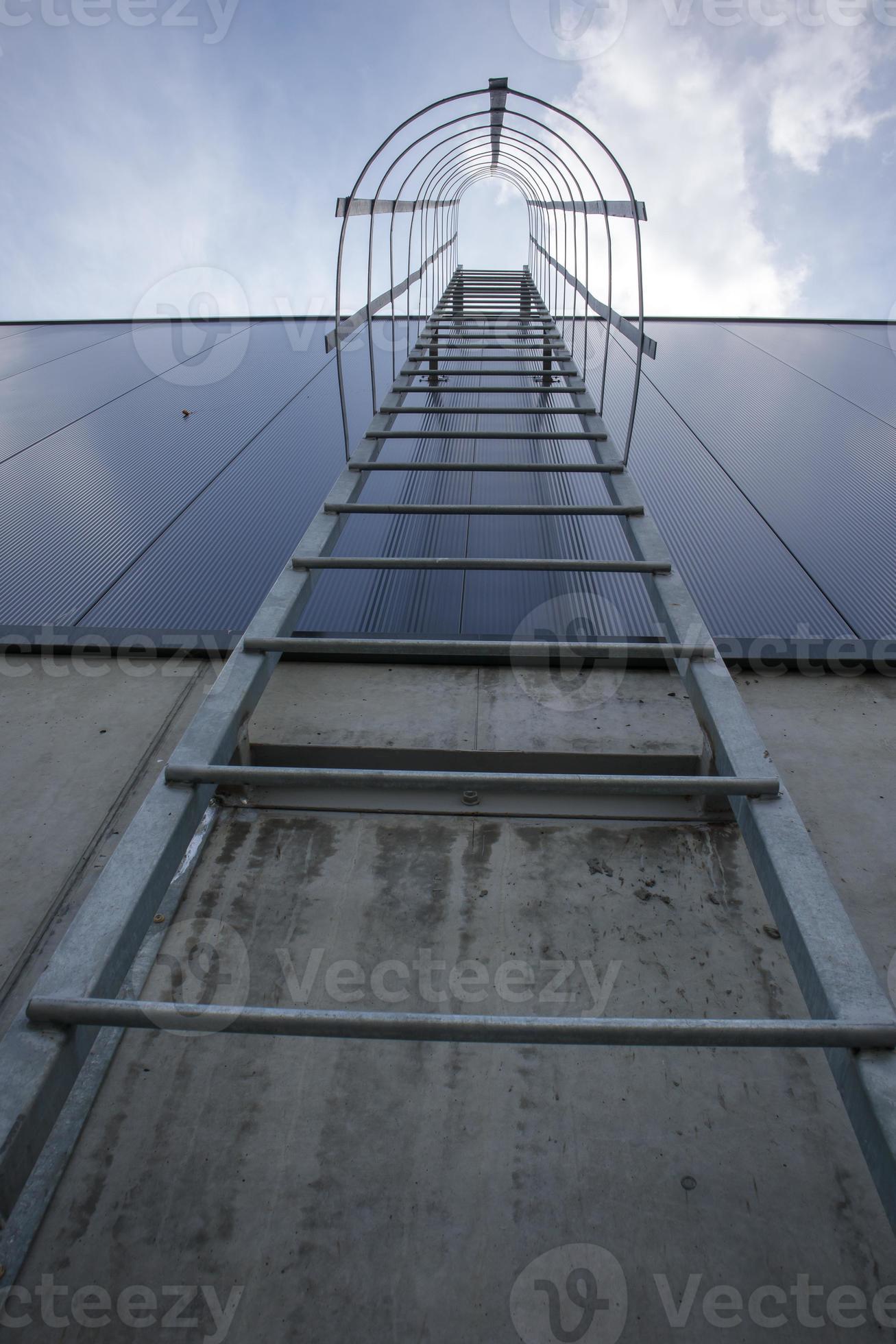 Fire escape on the industrial building above, bottom view. Stainless steel  handrails, roof ladder. Detail view of stairs with safety cage. Building  construction concept. 4538985 Stock Photo at Vecteezy