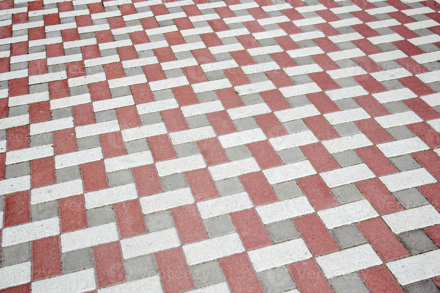 Concrete or paved newly laid gray and red paving slabs or stones for floors or walkways. Concrete paving slabs in the backyard or road paving. Garden brick path in the courtyard on a sandy foundation. photo