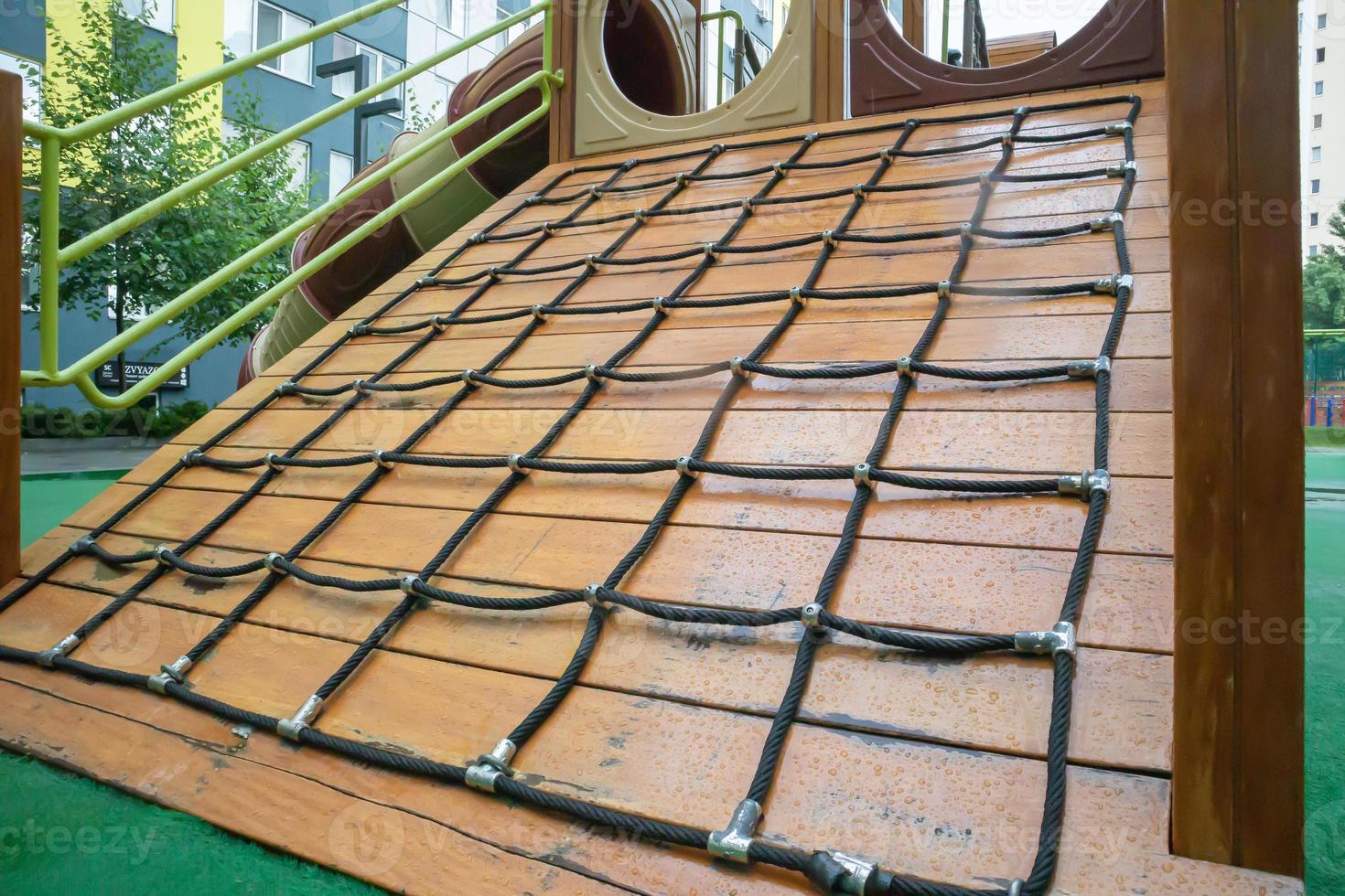 A courtyard of high-rise buildings with a modern and large playground made of wood and plastic on a rainy summer day without people. Empty outdoor playground. A place for children's games and sports. photo