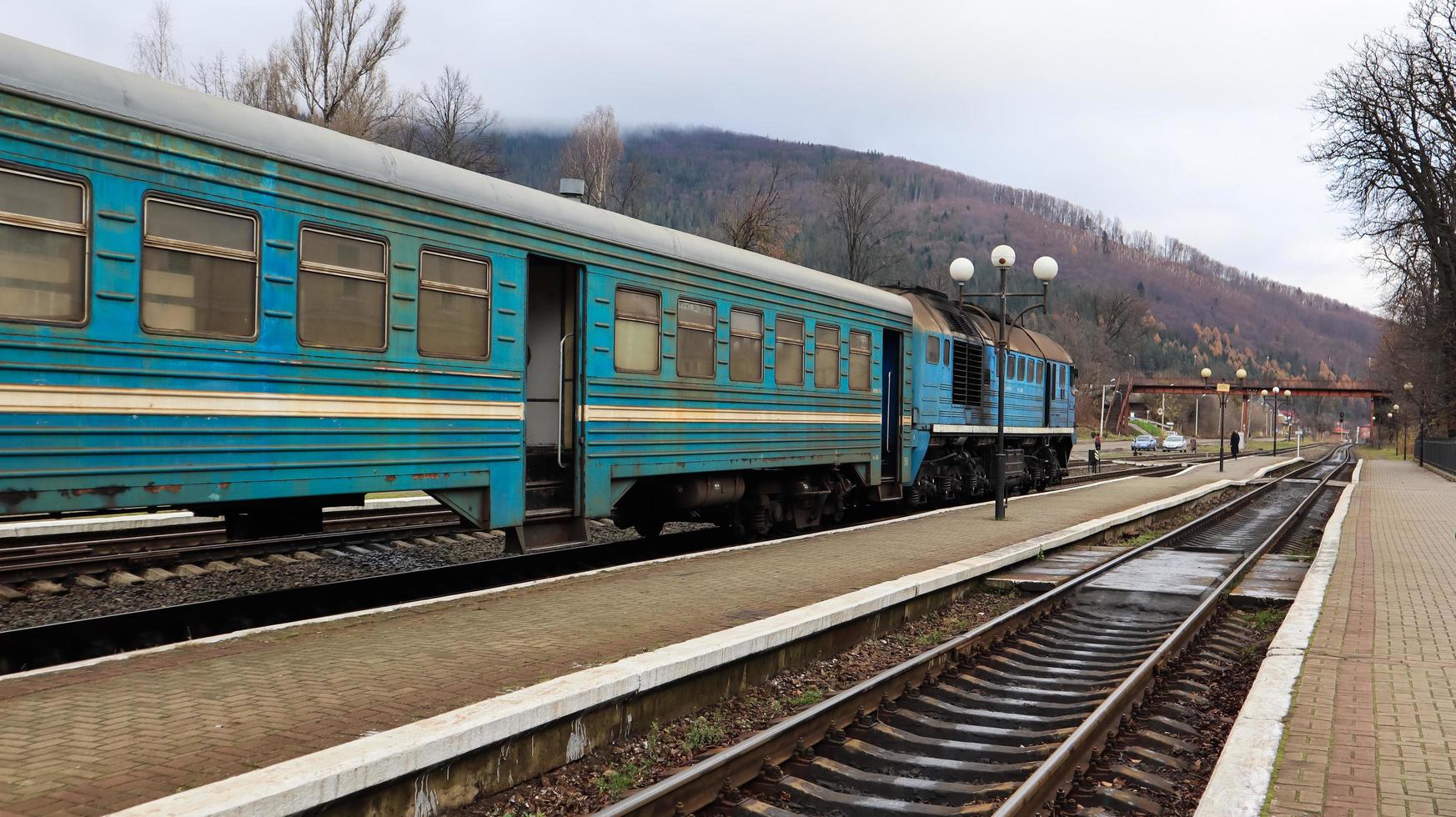 Ucrania, Yaremche - 20 de noviembre de 2019. Tren en la estación sobre un fondo de montañas. vagones de ferrocarril únicos en el andén de la ciudad de yaremche. Antiguo tren de pasajeros diesel. estación de ferrocarril. foto