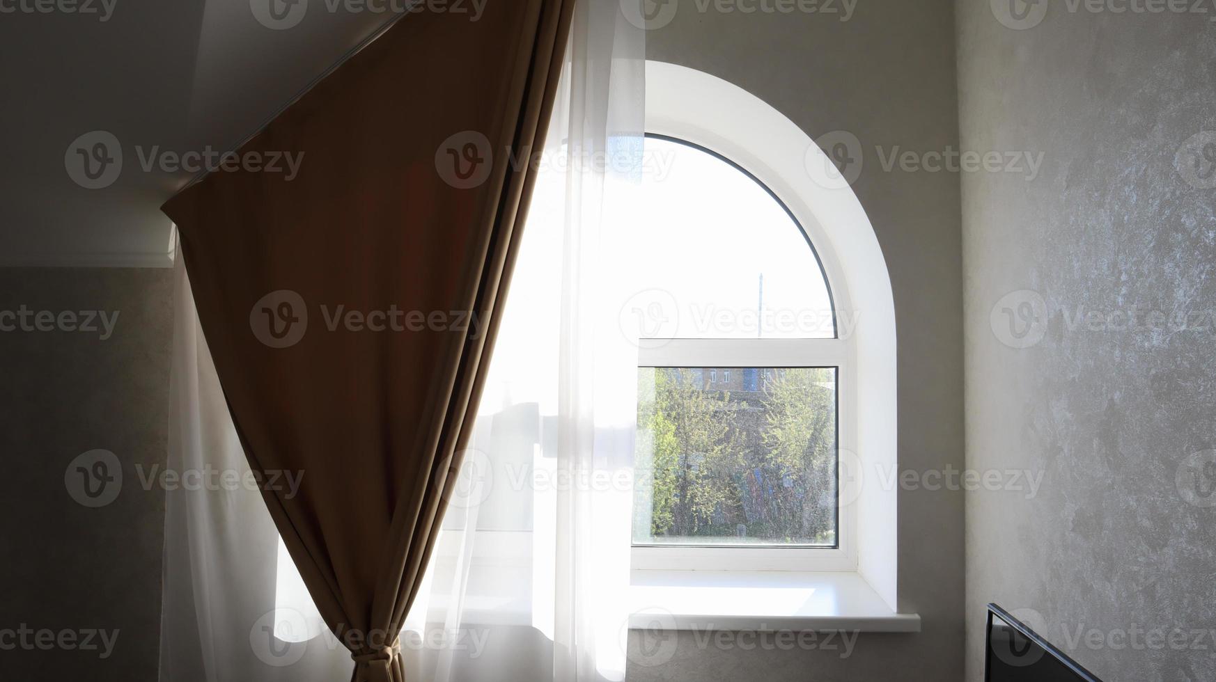 Arched window in the living room with tulle and curtain. Modern and bright bedroom interior. photo