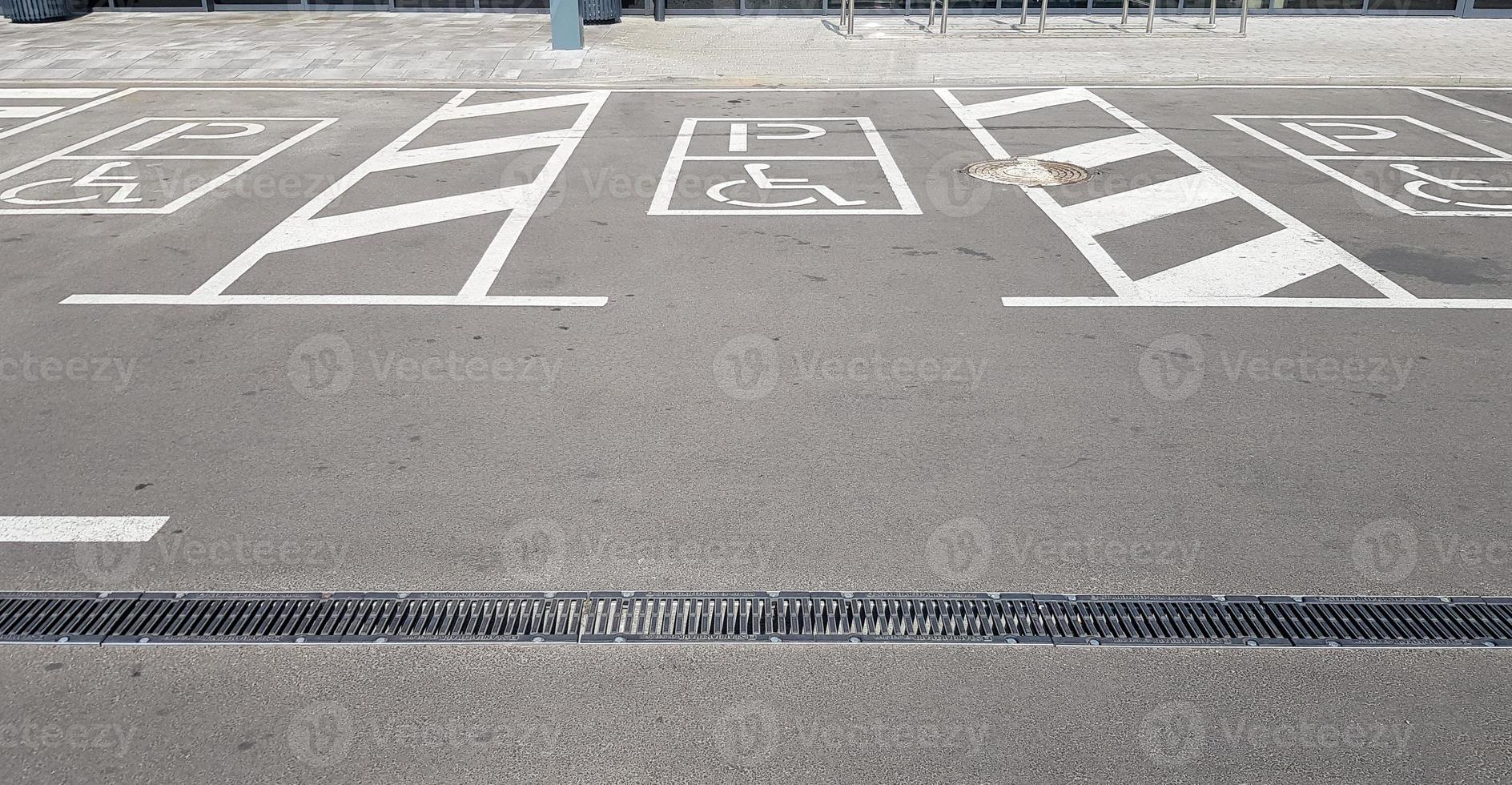 International handicap symbol in a parking lot of a shopping center. The space is clearly indicated on both sides by additional white diagonal stripes photo