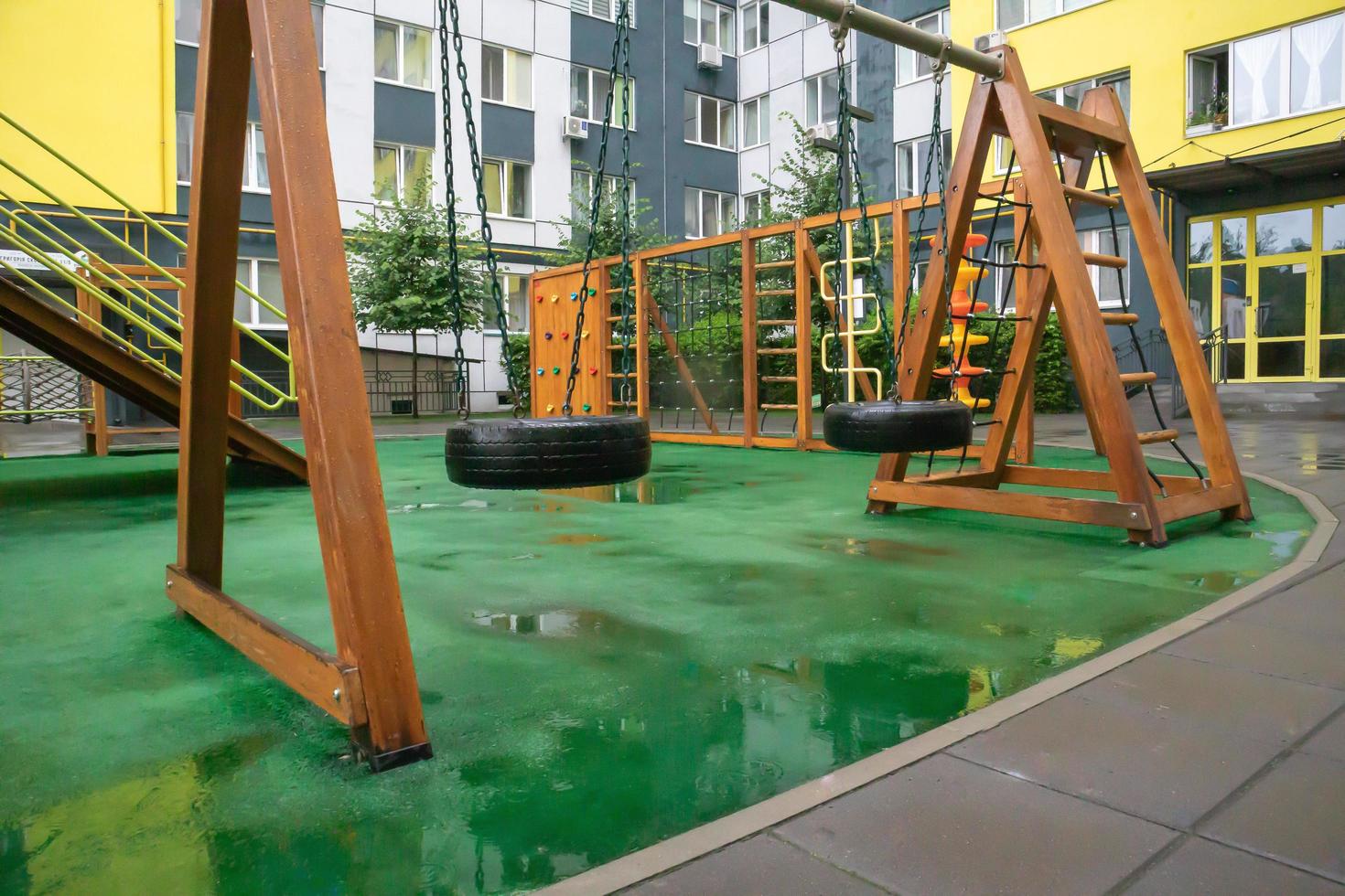 The courtyard of a high-rise building with a modern large playground made of wood and plastic on a rainy summer day without people. Ukraine, Kiev - August 19, 2021. photo