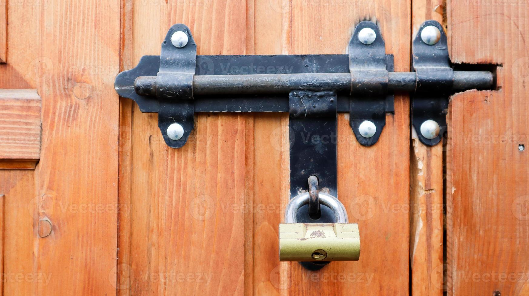 Old wooden door with a black metal bolt. Close up view of a lock and latch on a wooden door. Rustic wooden metal door latch. This sliding lock can be used on awnings, on desktops or on fences. photo