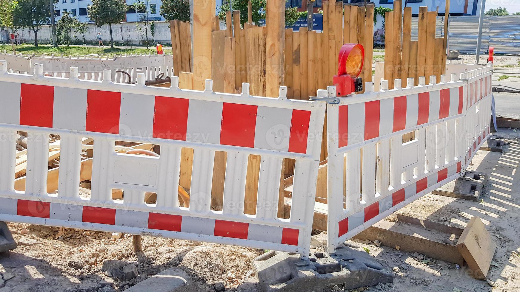 Plastic Protective barrier fences the site of road work. Red and white plastic fence near the street repair site. Construction work on the street, road repair, protective fence photo