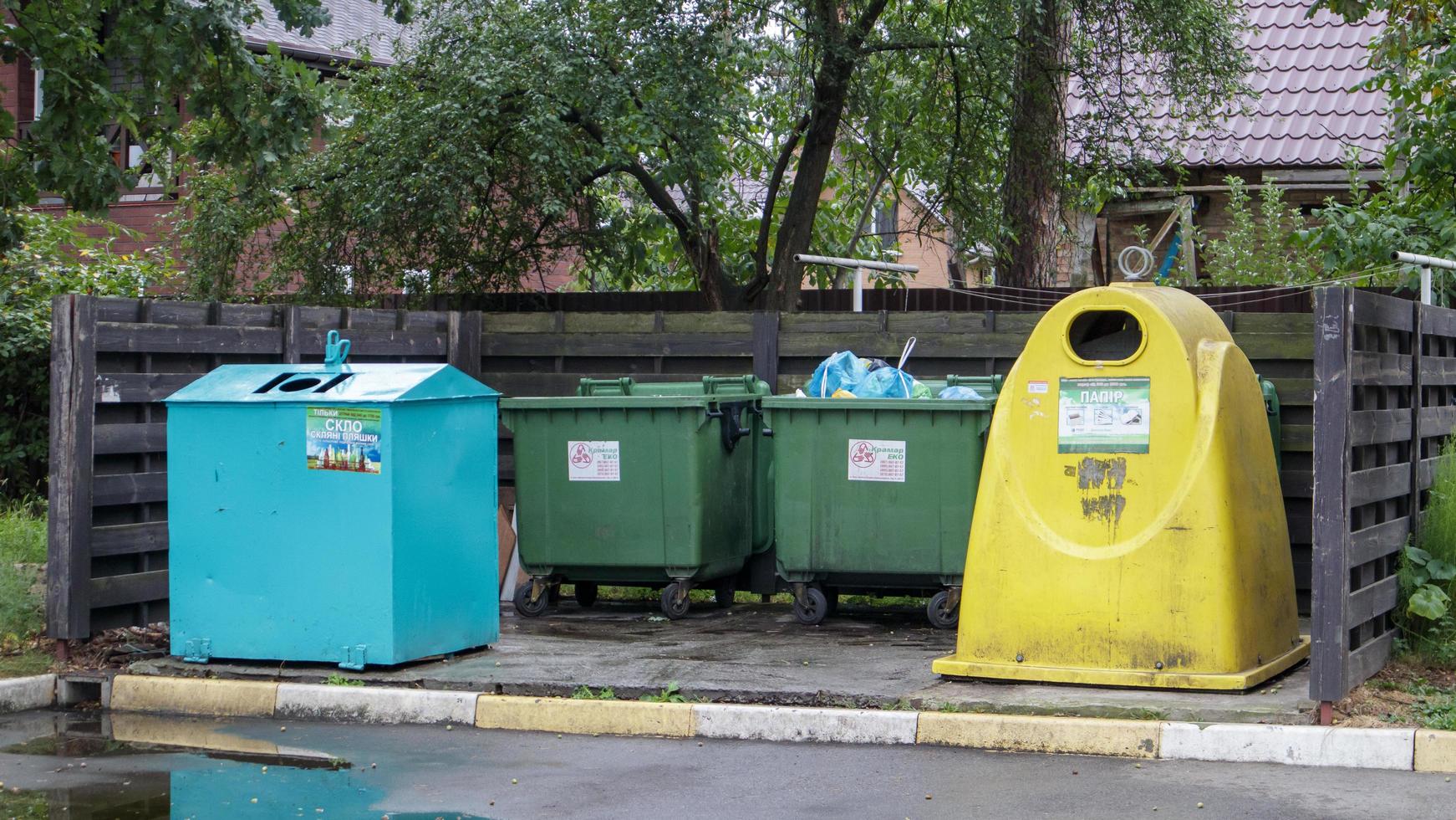 Cuatro cubos de basura de plástico y metal para clasificar los desechos en el patio de una calle residencial. botes de basura en el patio de un edificio residencial. Ucrania, Kiev - 29 de agosto de 2021. foto