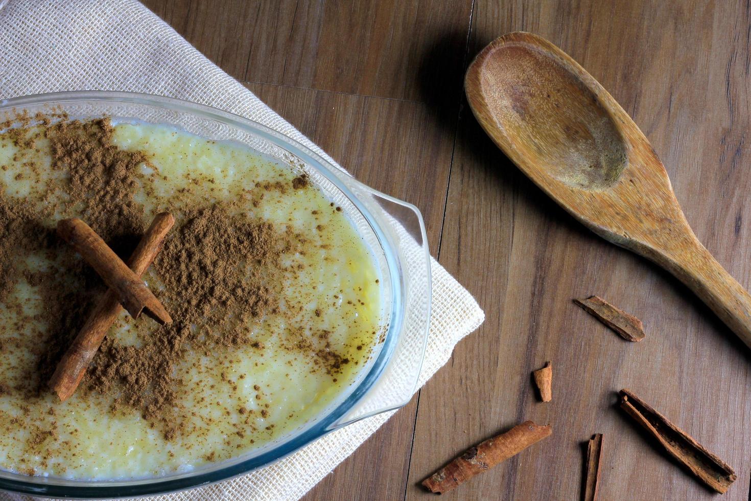 rice pudding with cinnamon on wooden table, accompanied by wooden spoon and cinnamon splinters photo