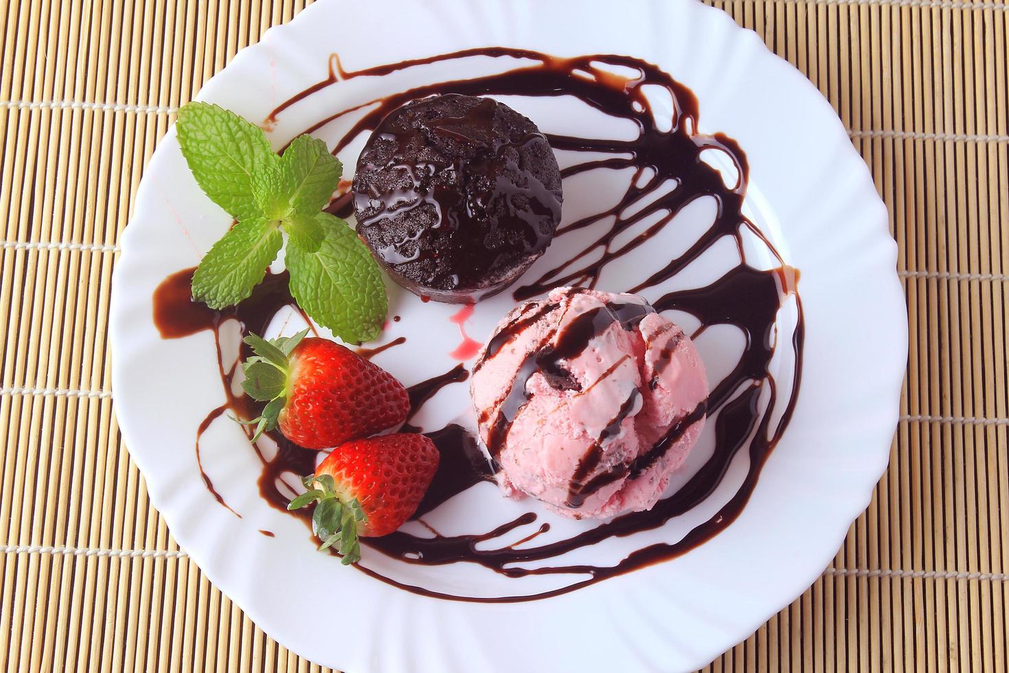 petit gateau with ice cream on white plate with strawberry over rustic wooden table photo