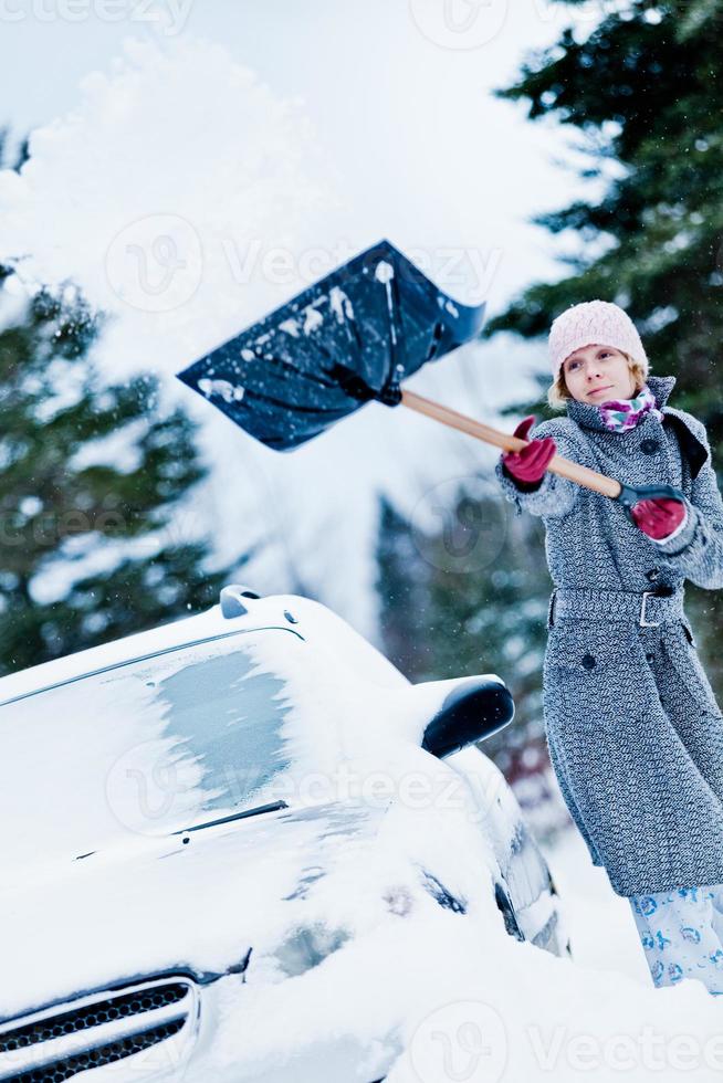 Car Stuck in the snow and a Woman Shoveling photo