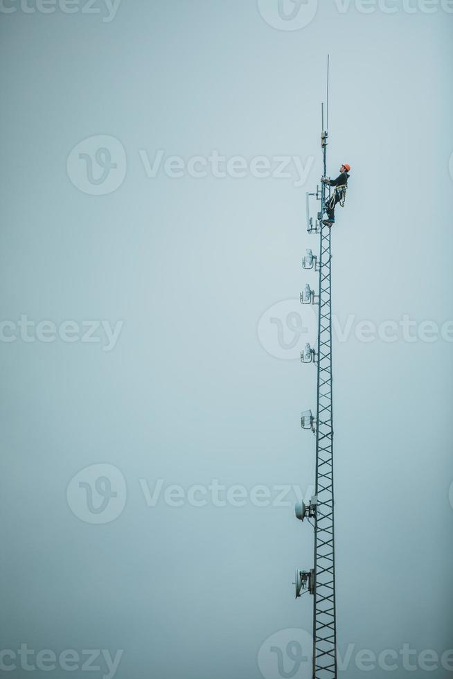 trabajador de telecomunicaciones subiendo torre de antena foto