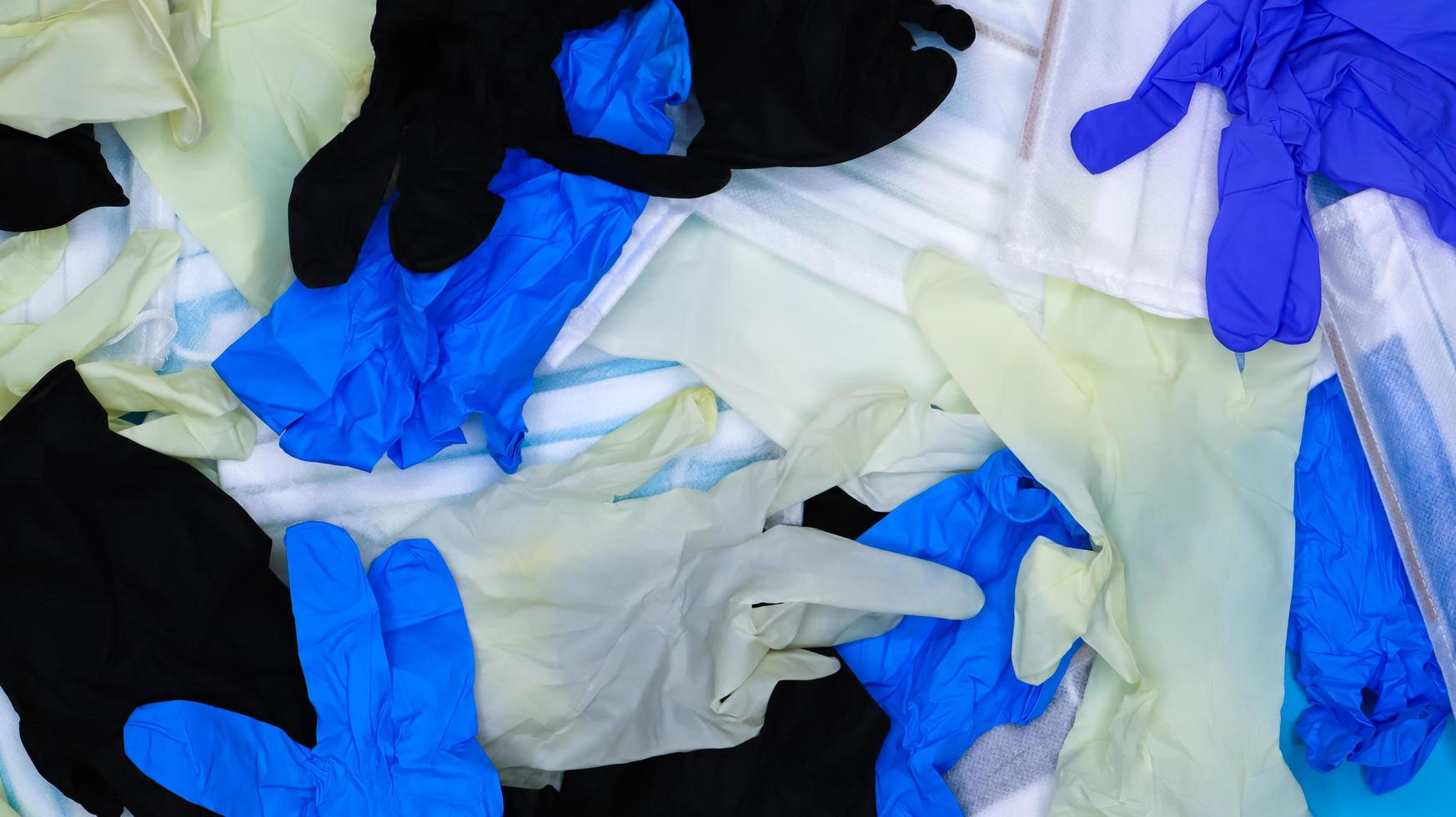 Los guantes quirúrgicos de látex arrugados multicolores y las máscaras protectoras médicas yacen en desorden. endecha plana. Remedios usados contra el virus covid-19. foto