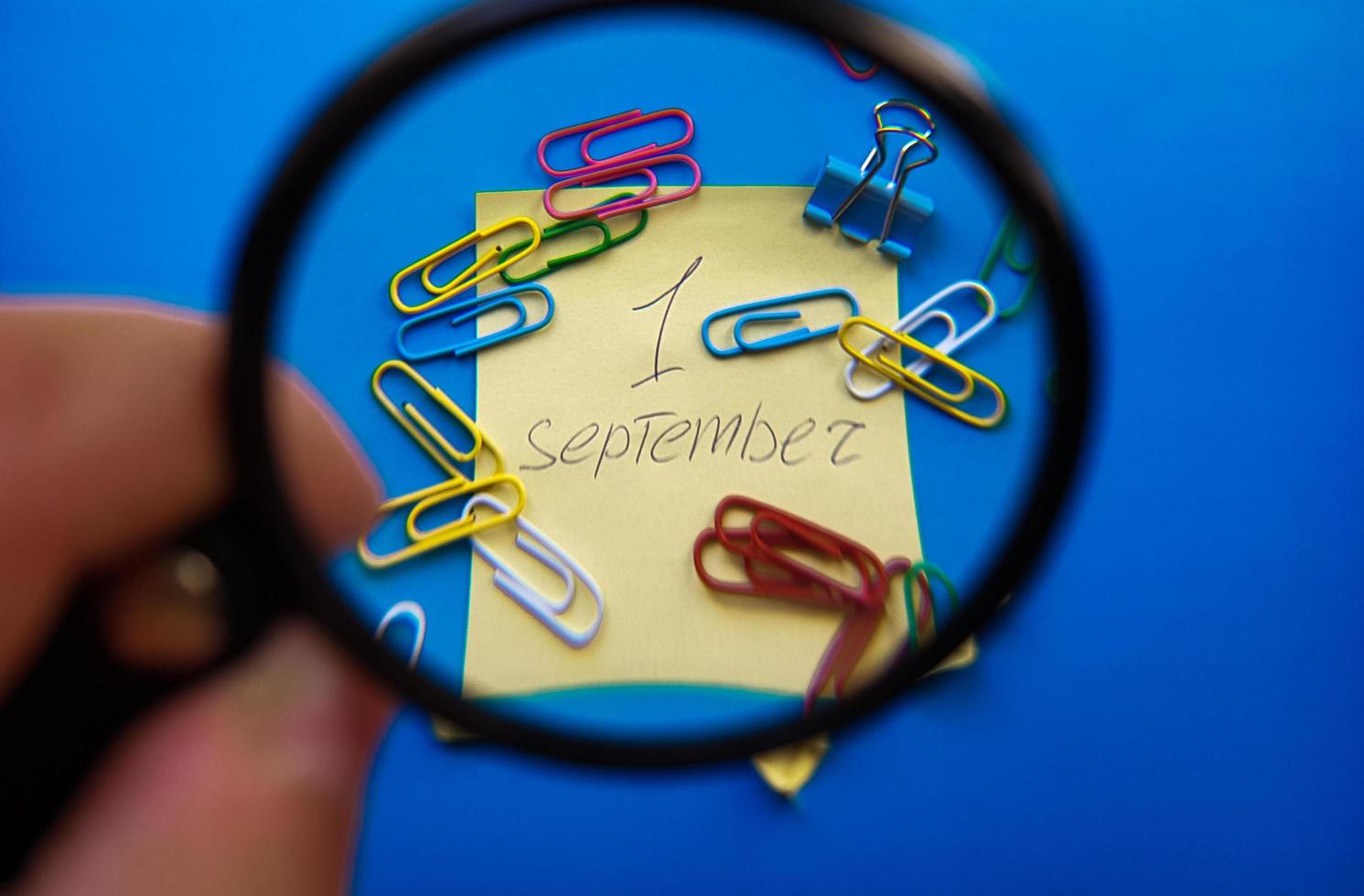 September 1st Day Concept. September 1, calendar with magnifier on a blue background and paper clips photo