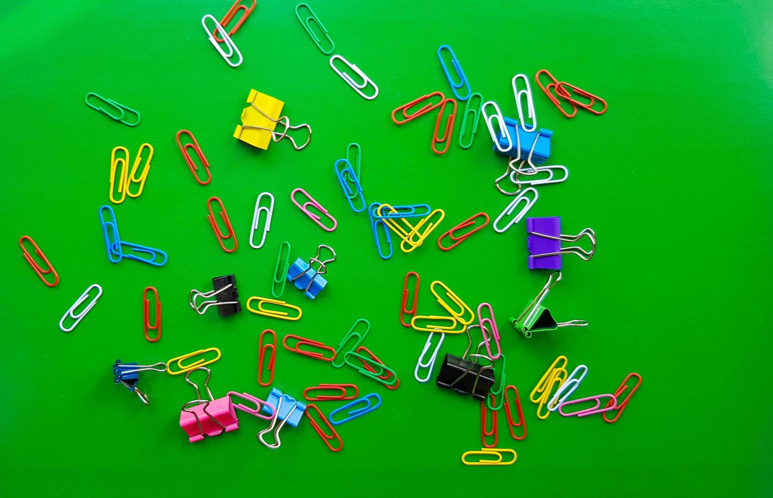 pile of paper clips isolated on green background, documents, office supplies concept, dirty office desk. Empty place for writing and text. Top view, layout. flat lay photo