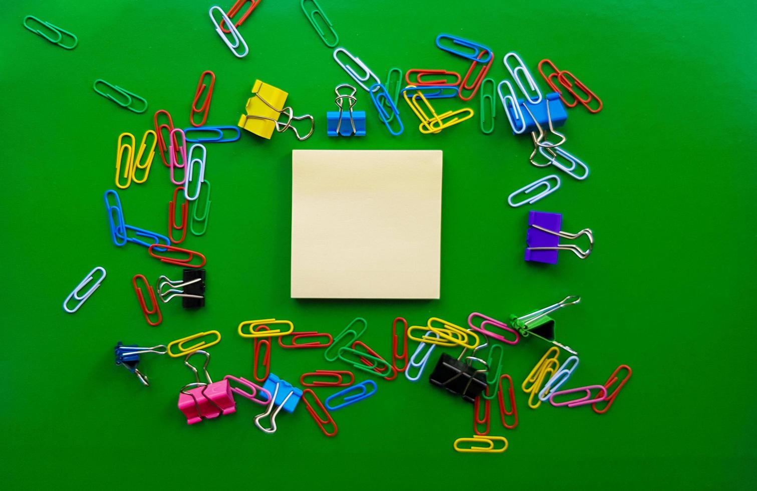 pile of paper clips isolated on green background, documents, office supplies concept, dirty office desk. Empty place for writing and text. Top view, layout. flat lay photo