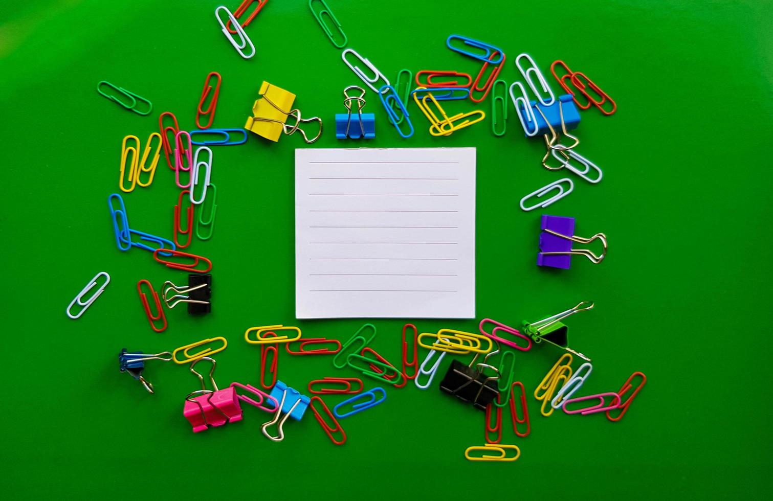 pile of paper clips isolated on green background, documents, office supplies concept, dirty office desk. Empty place for writing and text. Top view, layout. flat lay photo