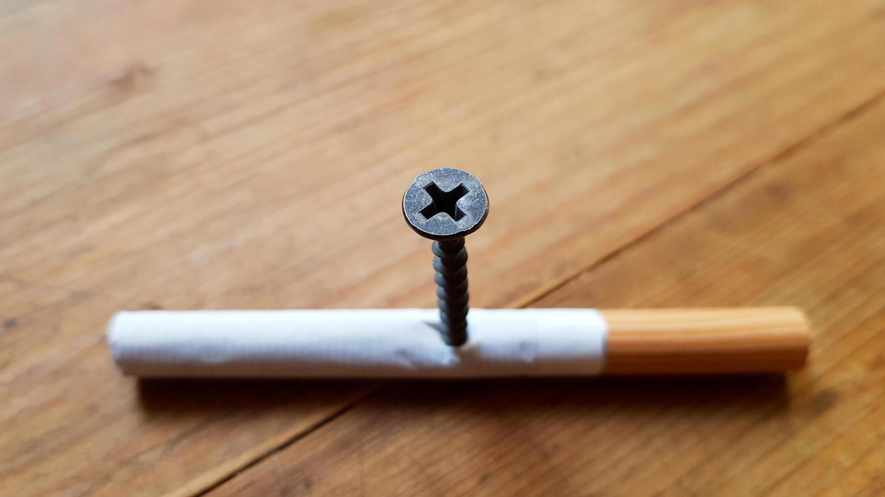 Screw and yellow background. Screw screwed into a cigarette. Anti-smoking concept photo