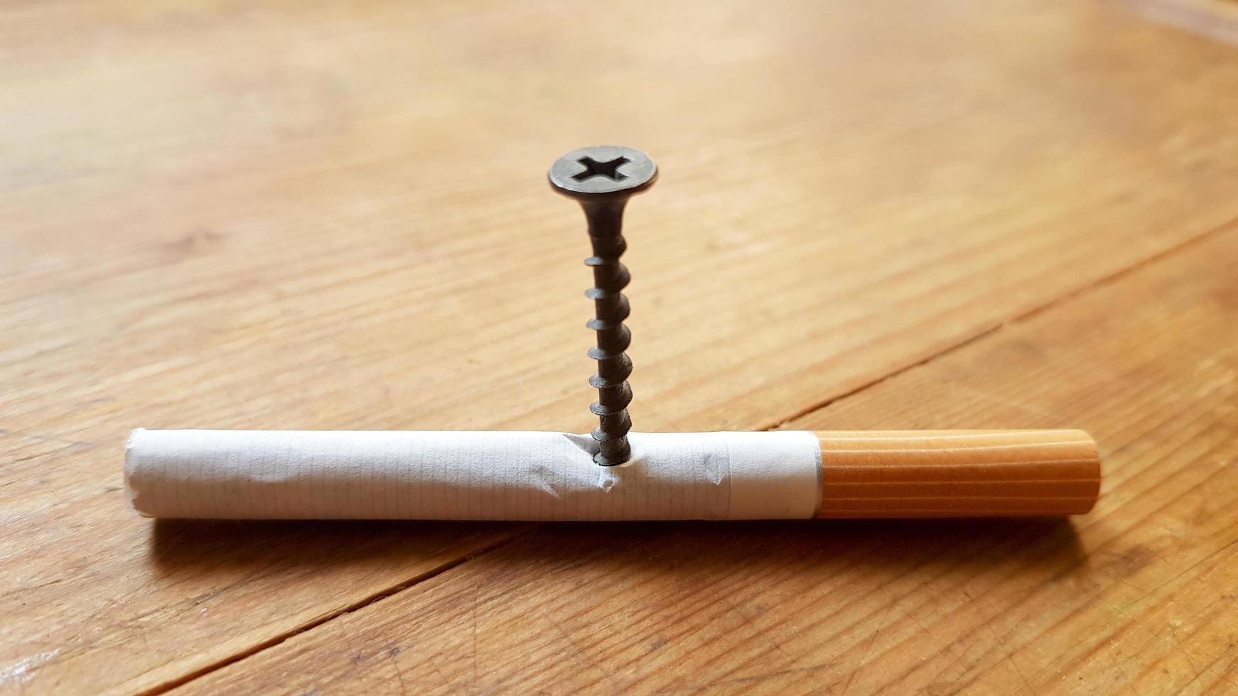 Screw and yellow background. Screw screwed into a cigarette. Anti-smoking concept photo