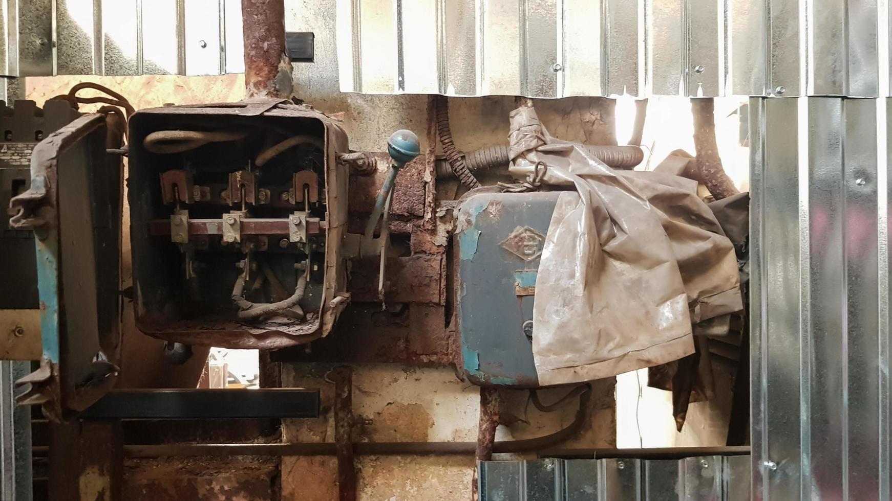 Viejo escudo eléctrico desmantelado y oxidado en una fábrica abandonada en el contexto del caos. foto