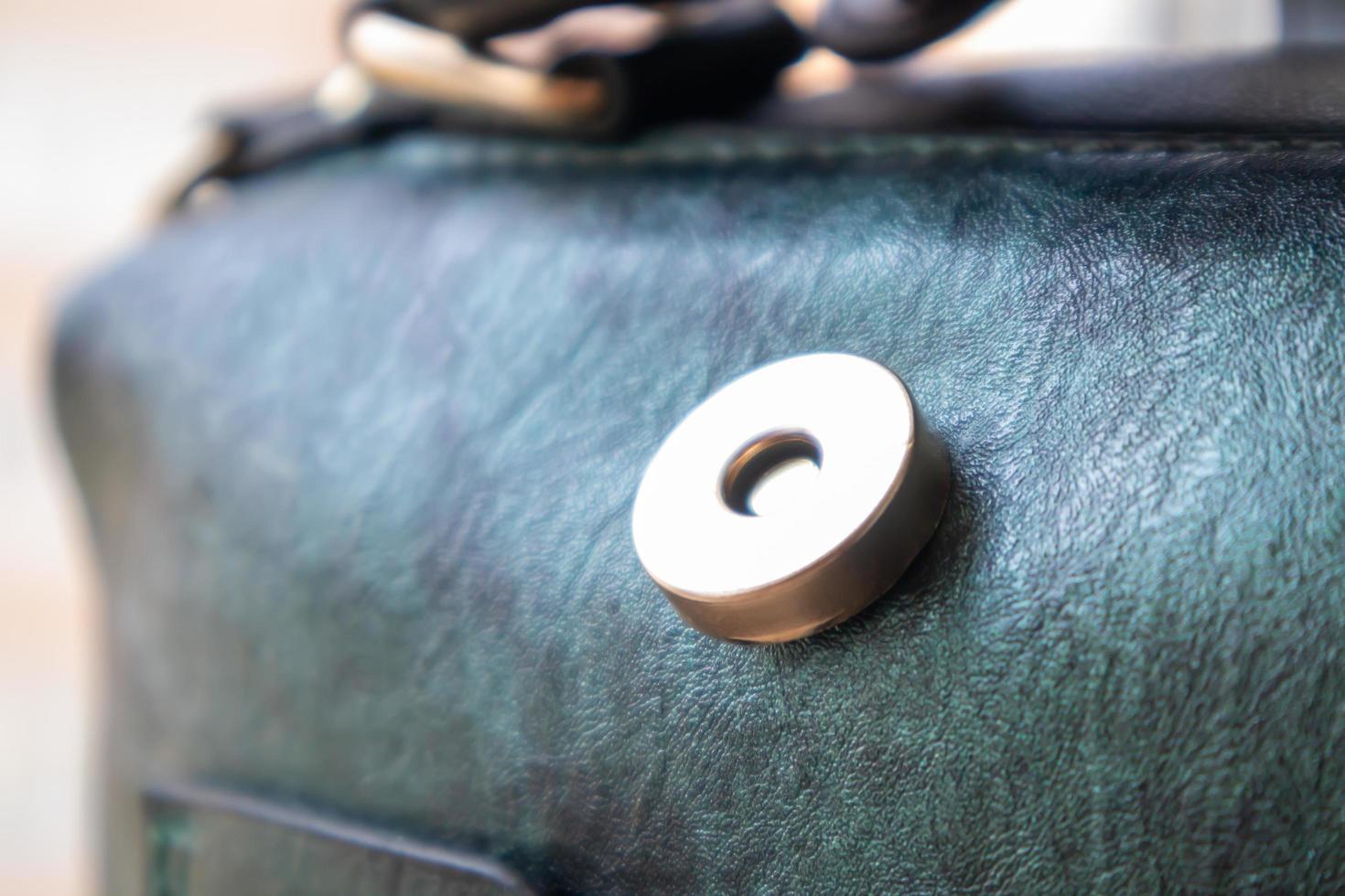 primer plano de cierre de botón magnético dorado abierto elegante bolso de hombro de cuero verde de moda para mujer. accesorios, detalle. foto
