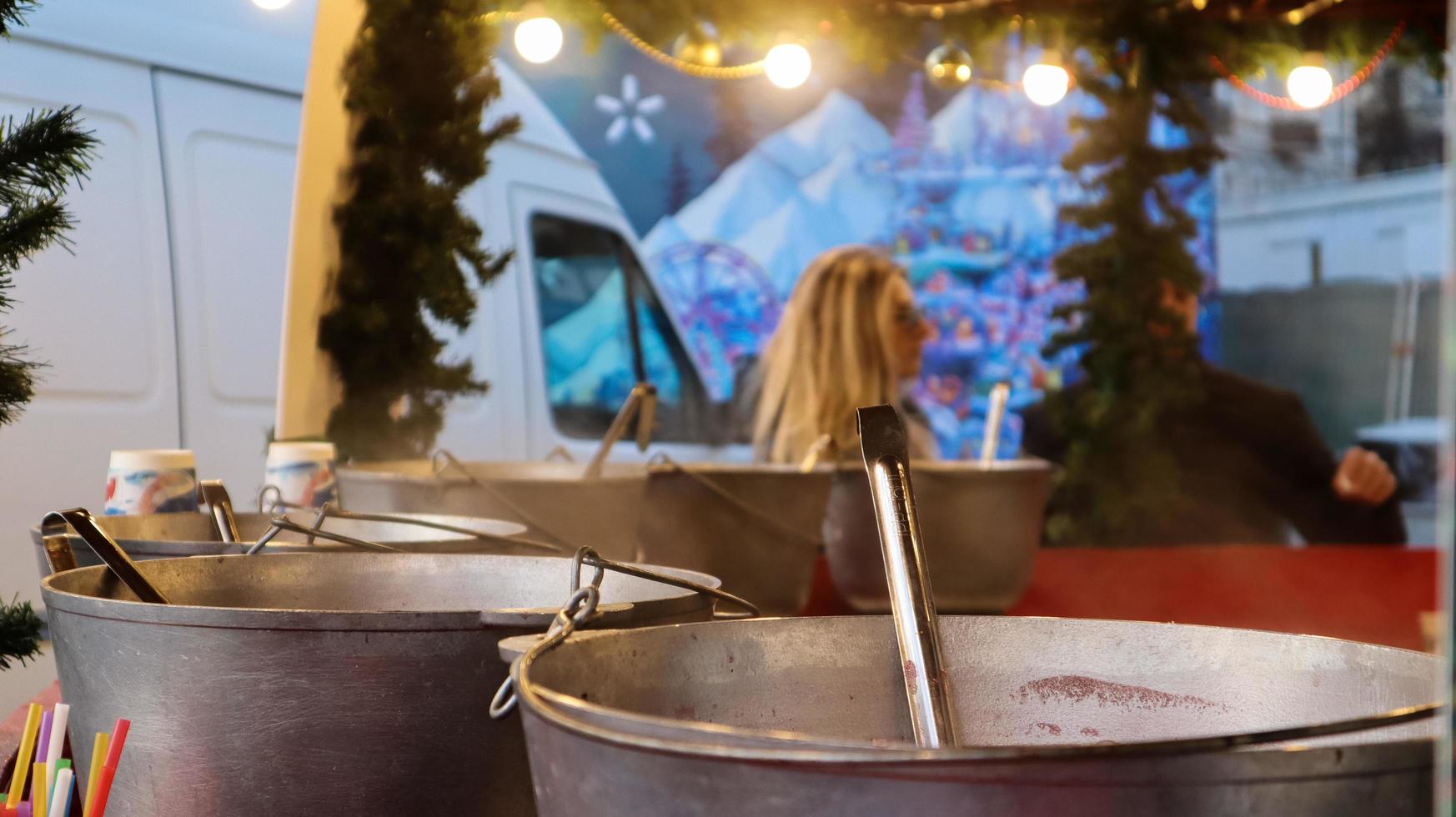 Mulled wine cooked on a fire outside. Vitamins in a winter drink. Street eatery at the Christmas market in winter. Hot mulled wine. Dense steam over cauldrons of hot wine. photo
