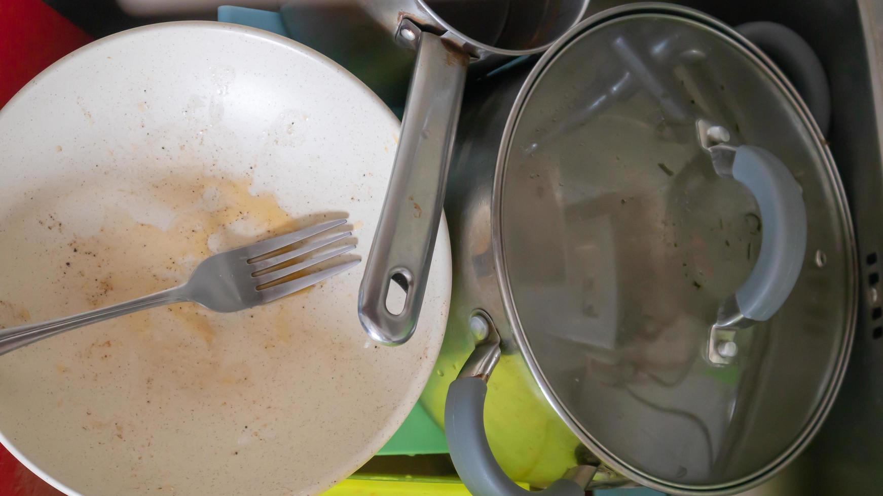 The kitchen utensils in the wash basin need to be washed. A pile of dirty dishes in the kitchen sink. Kitchen utensils need washing. Homework concept. photo