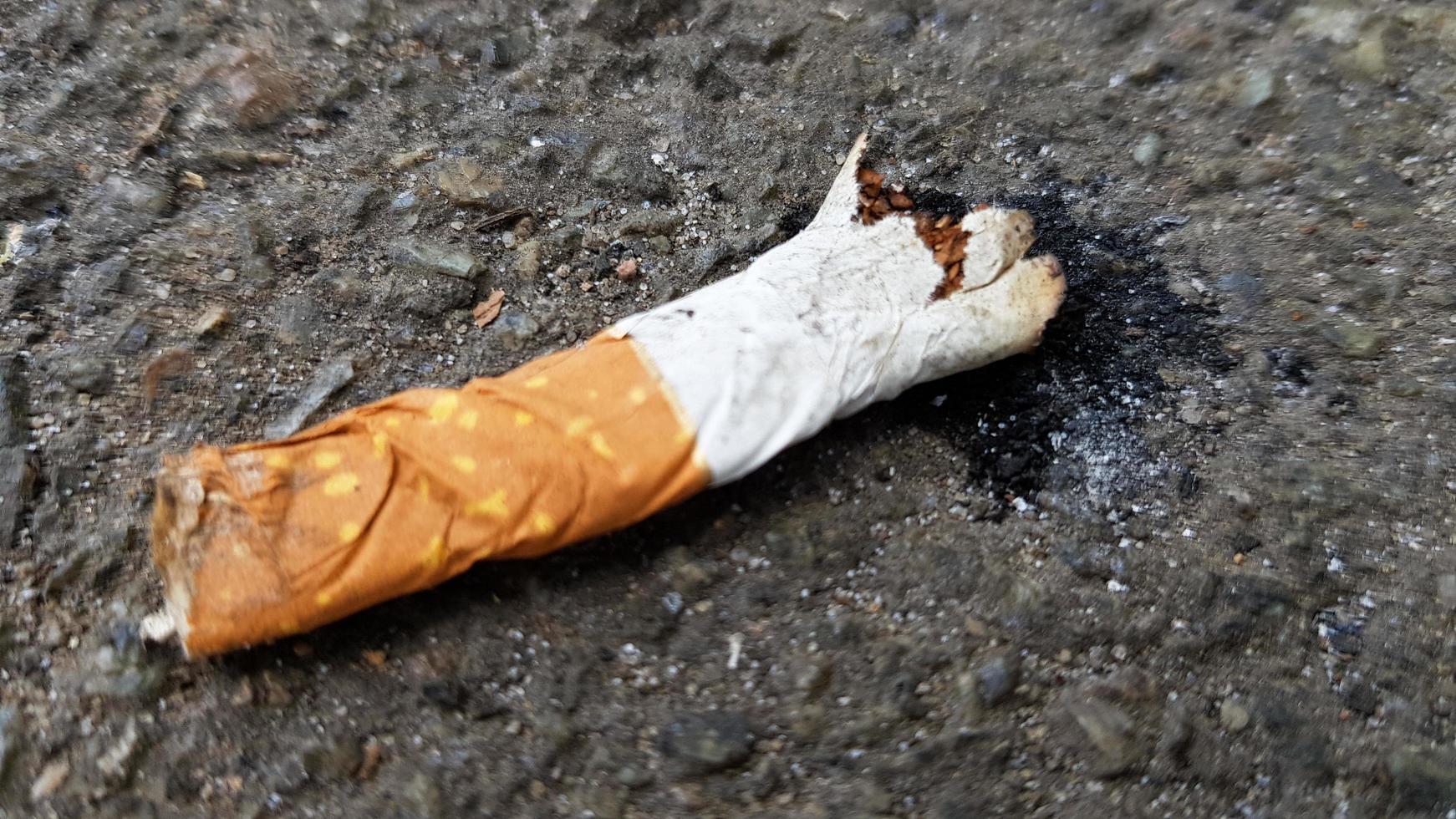 Close up of a broken cigarette butt on asphalt with copy space. International No Tobacco Day. World Day against cigarettes, nicotine and tobacco photo