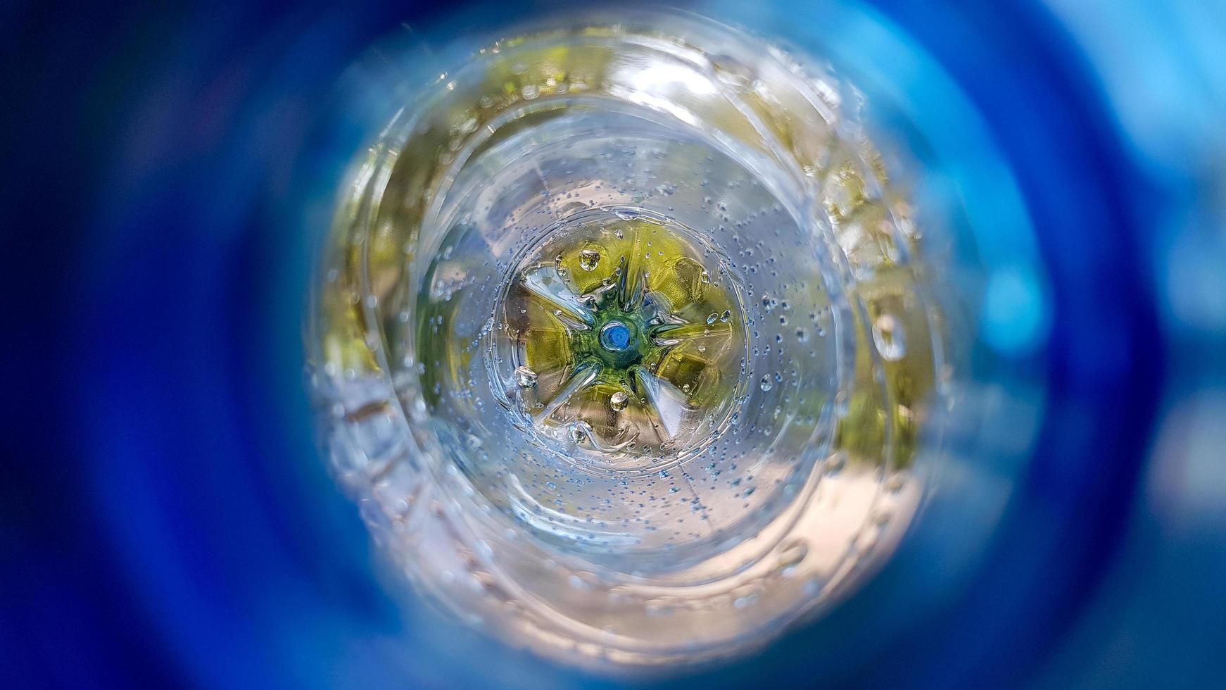 Long background with a plastic blue bottle with water drops inside photo
