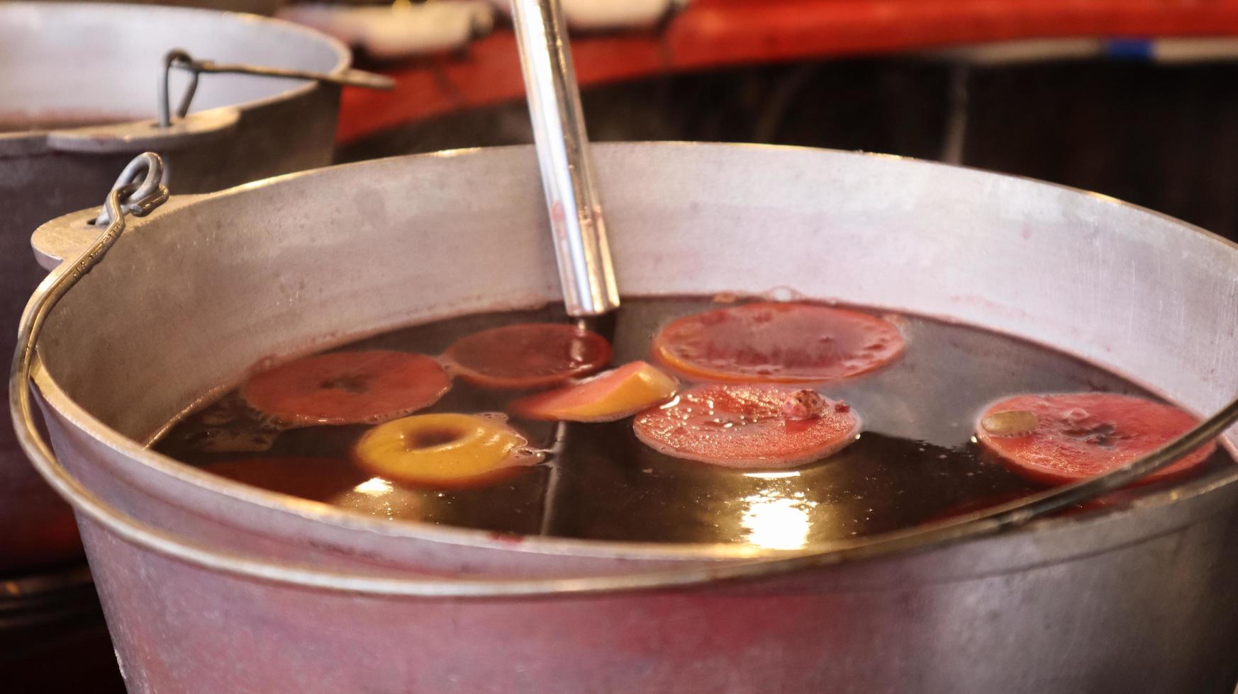 Mulled wine cooked on a fire outside. Vitamins in a winter drink. Street eatery at the Christmas market in winter. Hot mulled wine. Dense steam over cauldrons of hot wine. photo