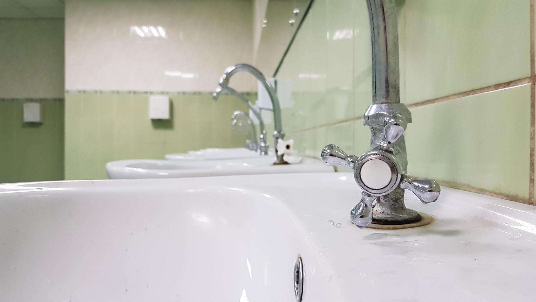 Old and dirty faucet and white ceramic washbasin sink, concept of cleaning, repairing or replacing a bathroom, toilet. photo