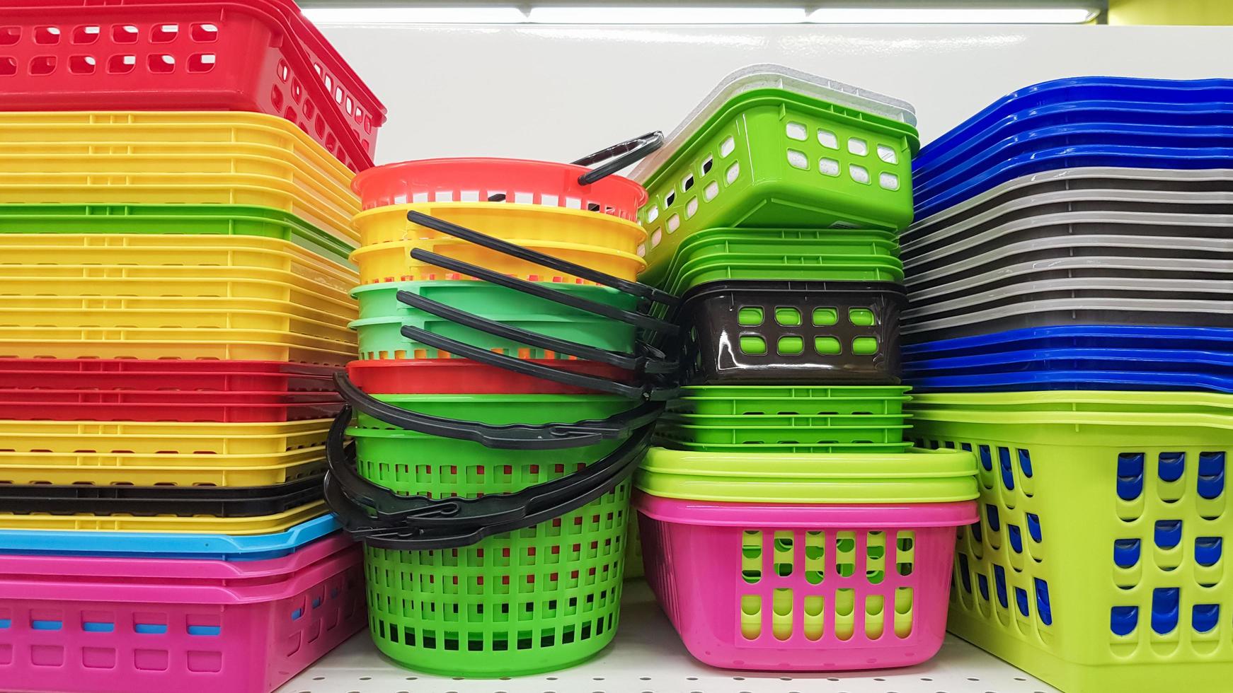 Multi-colored plastic containers of different shapes and sizes with and without lids, stacked in a pile on a store window. Sale of boxes for storage and cleaning. Modern kitchen utensils photo