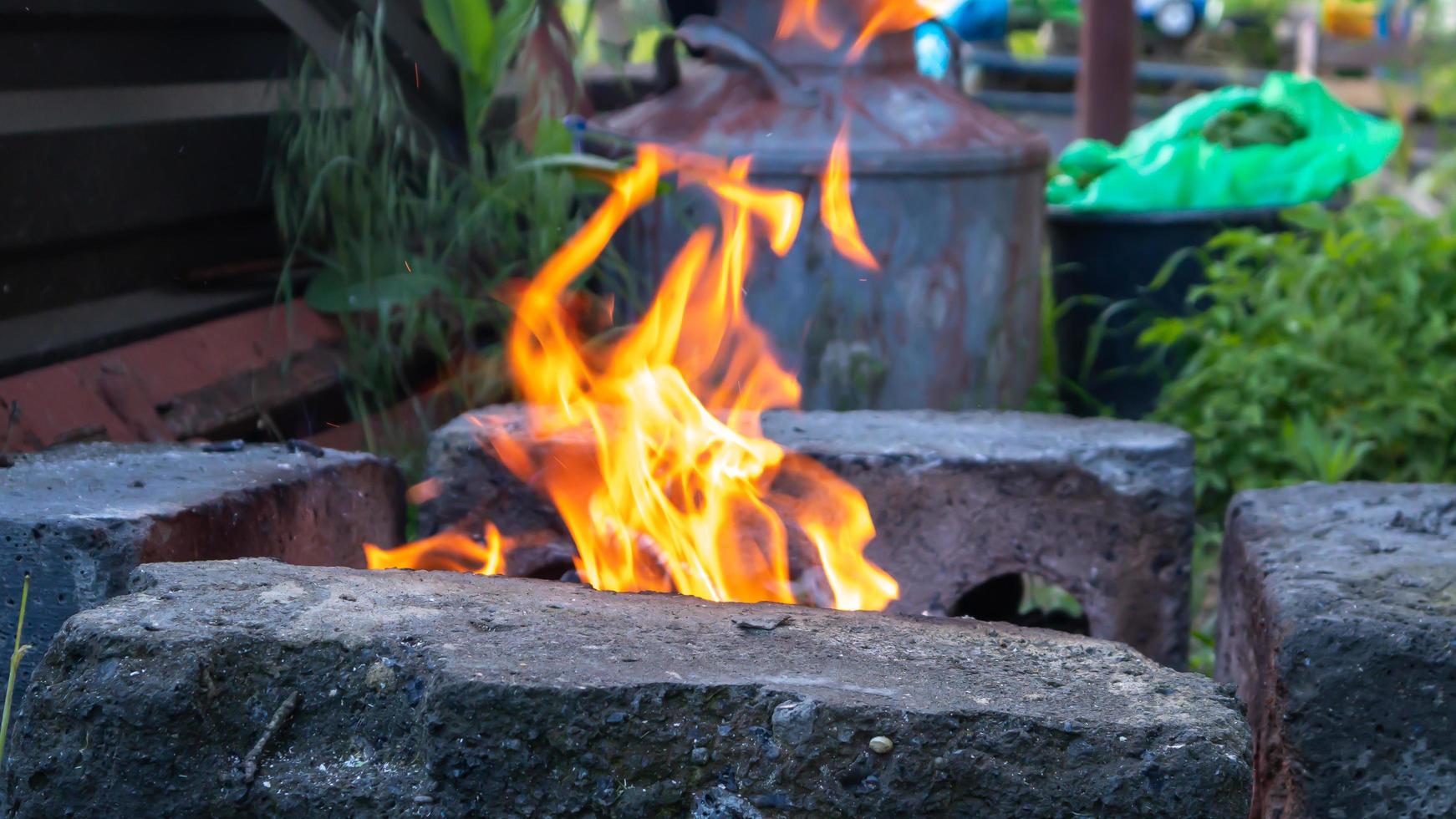 Fire blazes in a homemade barbecue grill in the backyard. Bonfire for cooking food on an open fire on wood. Camping. Camping concept. photo