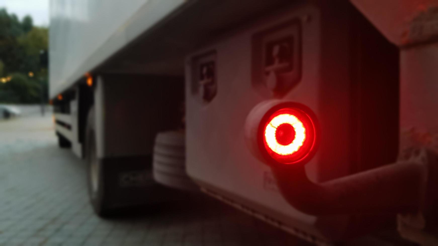 Close-up shot of the rear round red marker light of a truck. Rear light for a truck. The background is blurred. The concept of safe travel on the road at night. photo