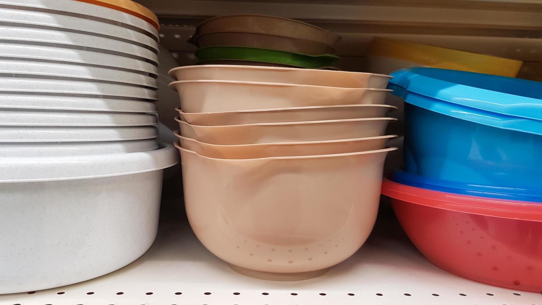 Multi-colored plastic containers of different shapes and sizes with and without lids, stacked in a pile on a store window. Sale of boxes for storage and cleaning. Modern kitchen utensils photo