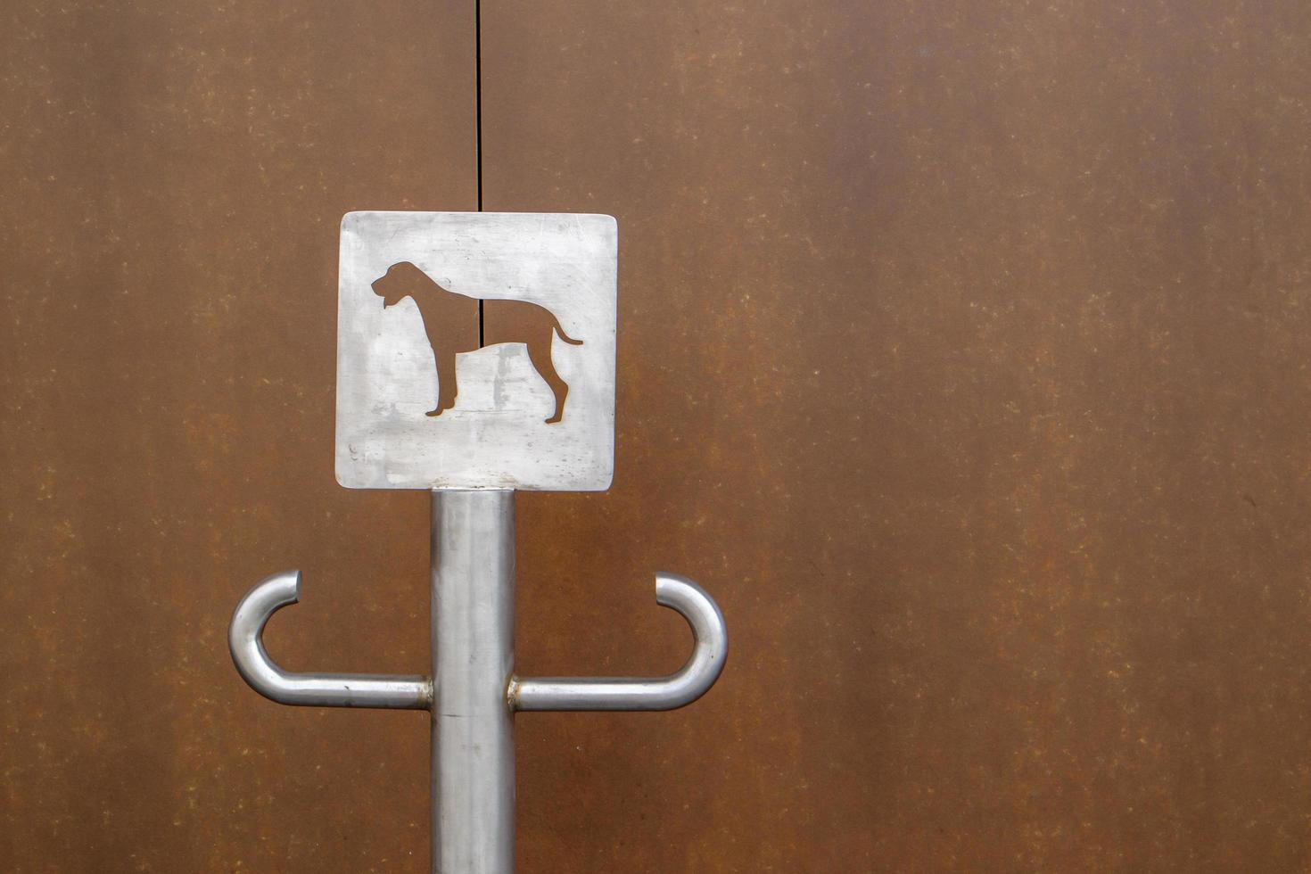 Close-up of an outdoor dog parking sign. A place for a leash for dogs waiting for their owners on the street. Attach a leash, in public places or at the entrance to the store. Copy space. photo