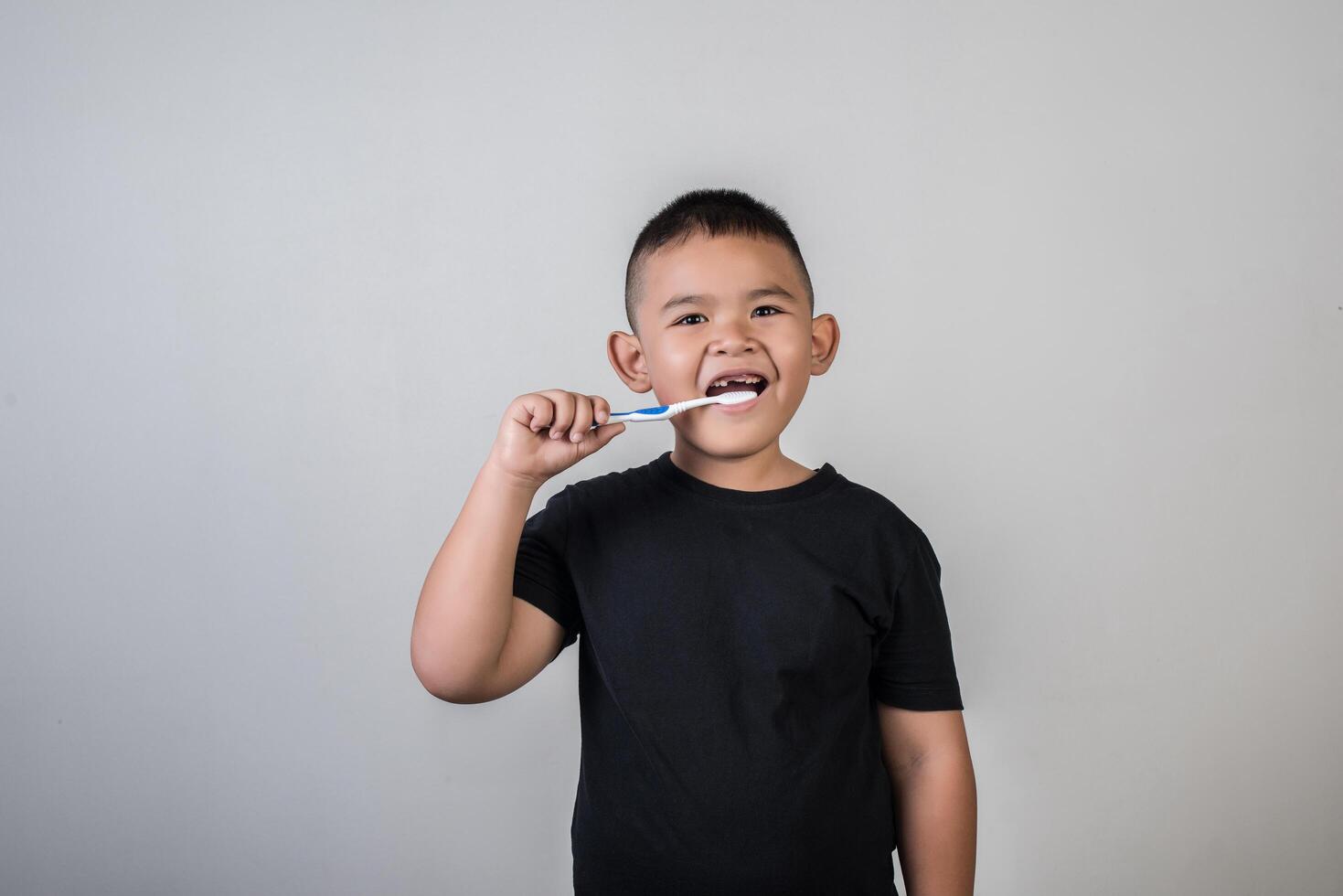 Little boy brushing his teeth in studio photo