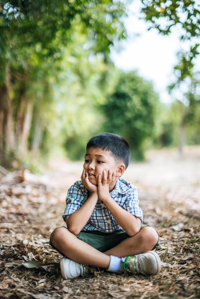 Happy boy sitting and thinking alone in the park photo