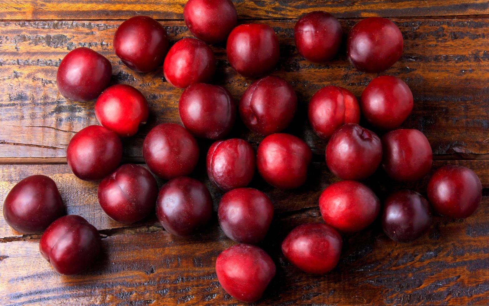 raw and fresh organic plums on rustic wooden table. Top view photo