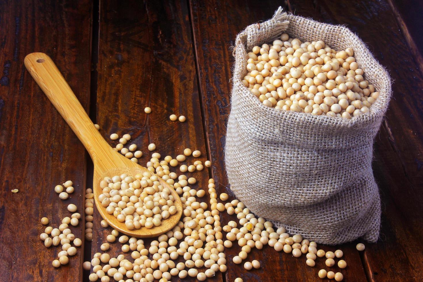 raw and fresh soy beans in rustic fabric bag on wooden table. Closeup photo