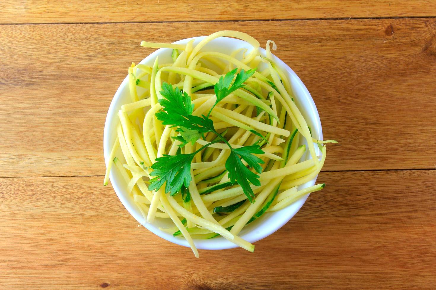 Homemade raw zucchini pasta in ceramic bowl on rustic wooden table. concept of healthy food photo