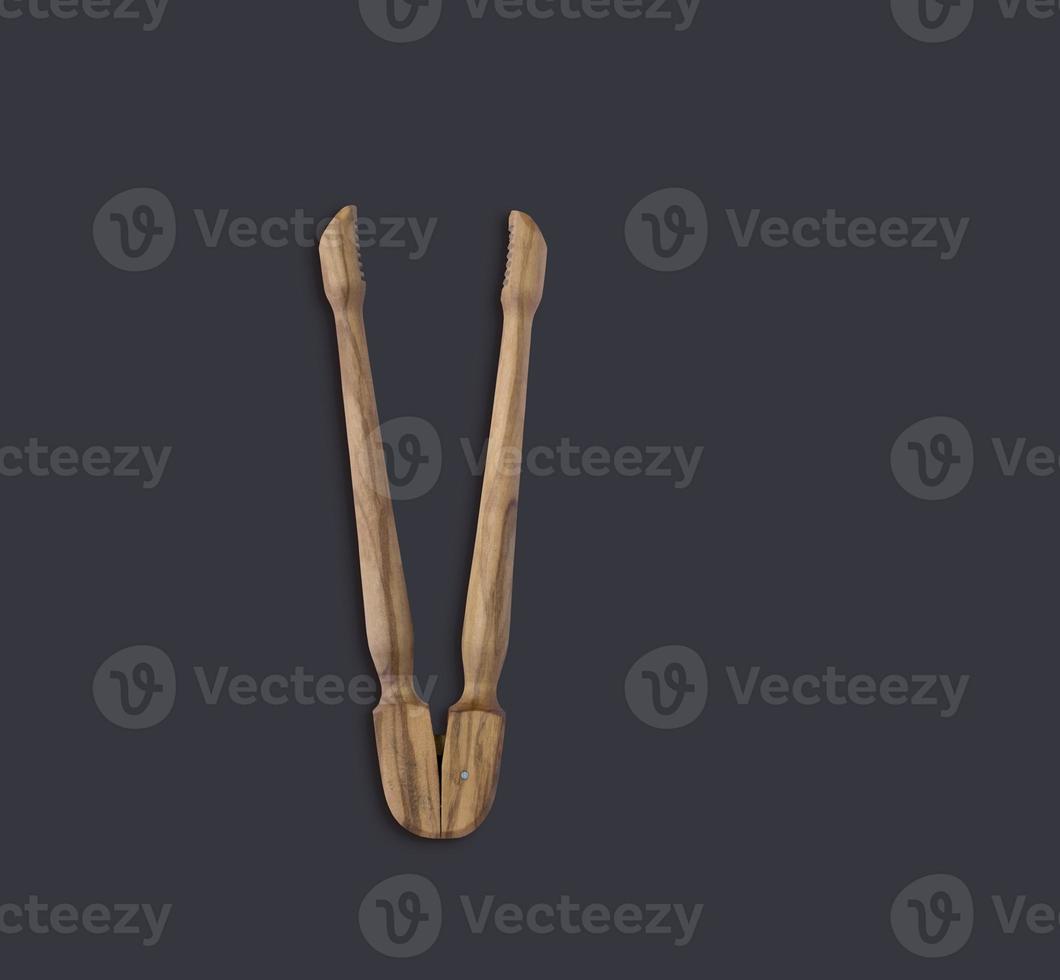 Top up view olive wooden tongs isolated on dark background. suitable for your design element. photo