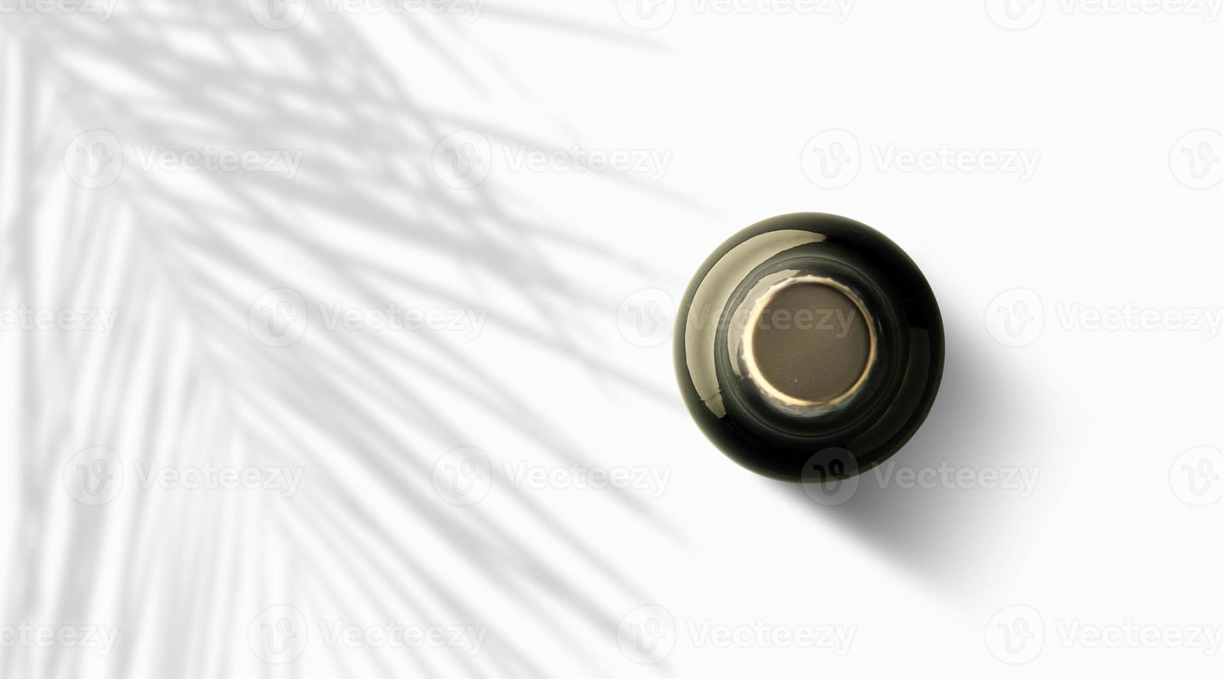 Top up view dark brown beer bottle under palm tree isolated on white. photo